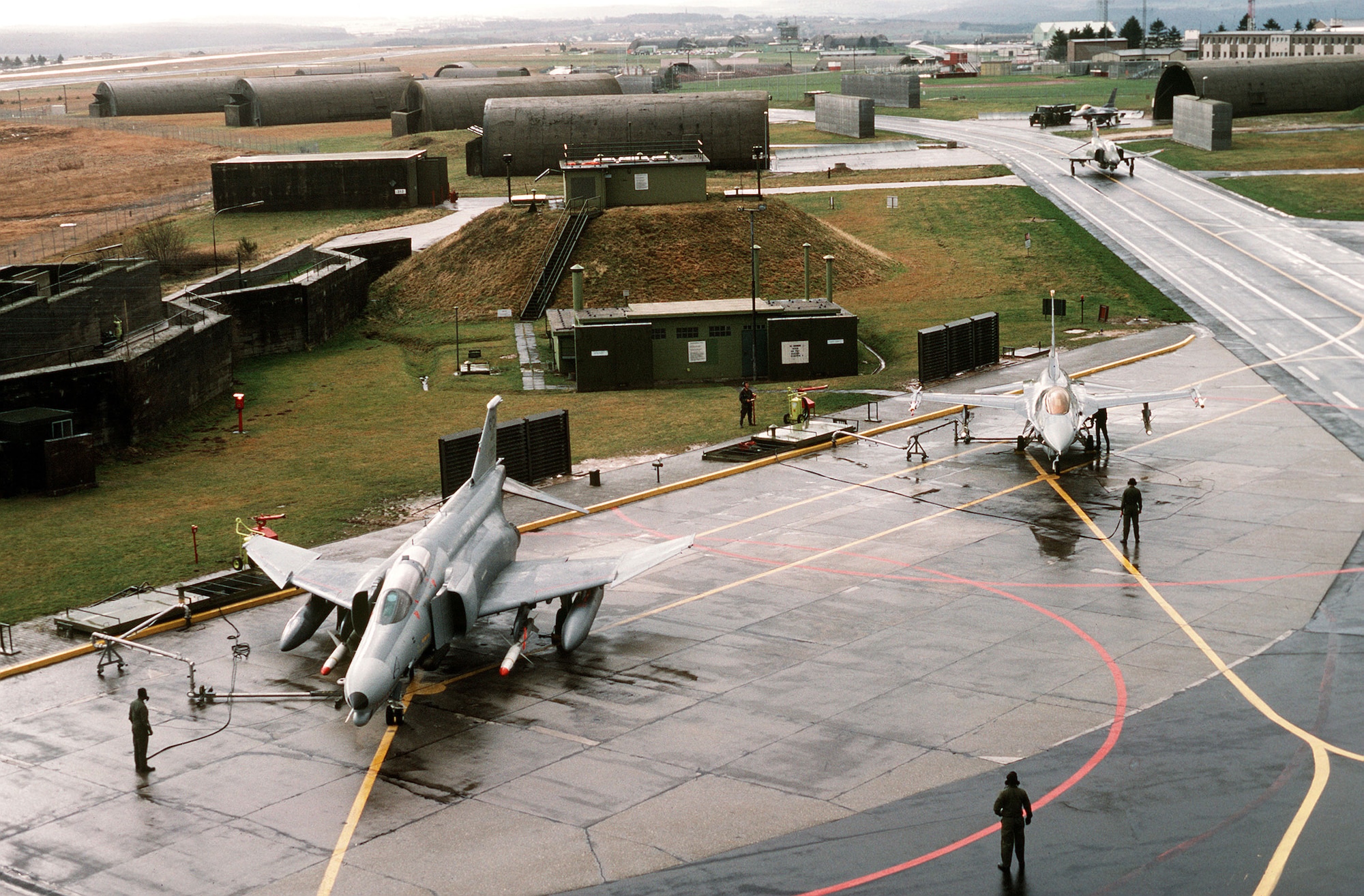 An F-4G Wild Weasel fighter (foreground) and an F-16 Fighting Falcon are serviced on the flight line prior to departing for Saudi Arabia during Operation Desert Shield. (U.S. Air Force photo/Tech. Sgt. Fernando Serna)