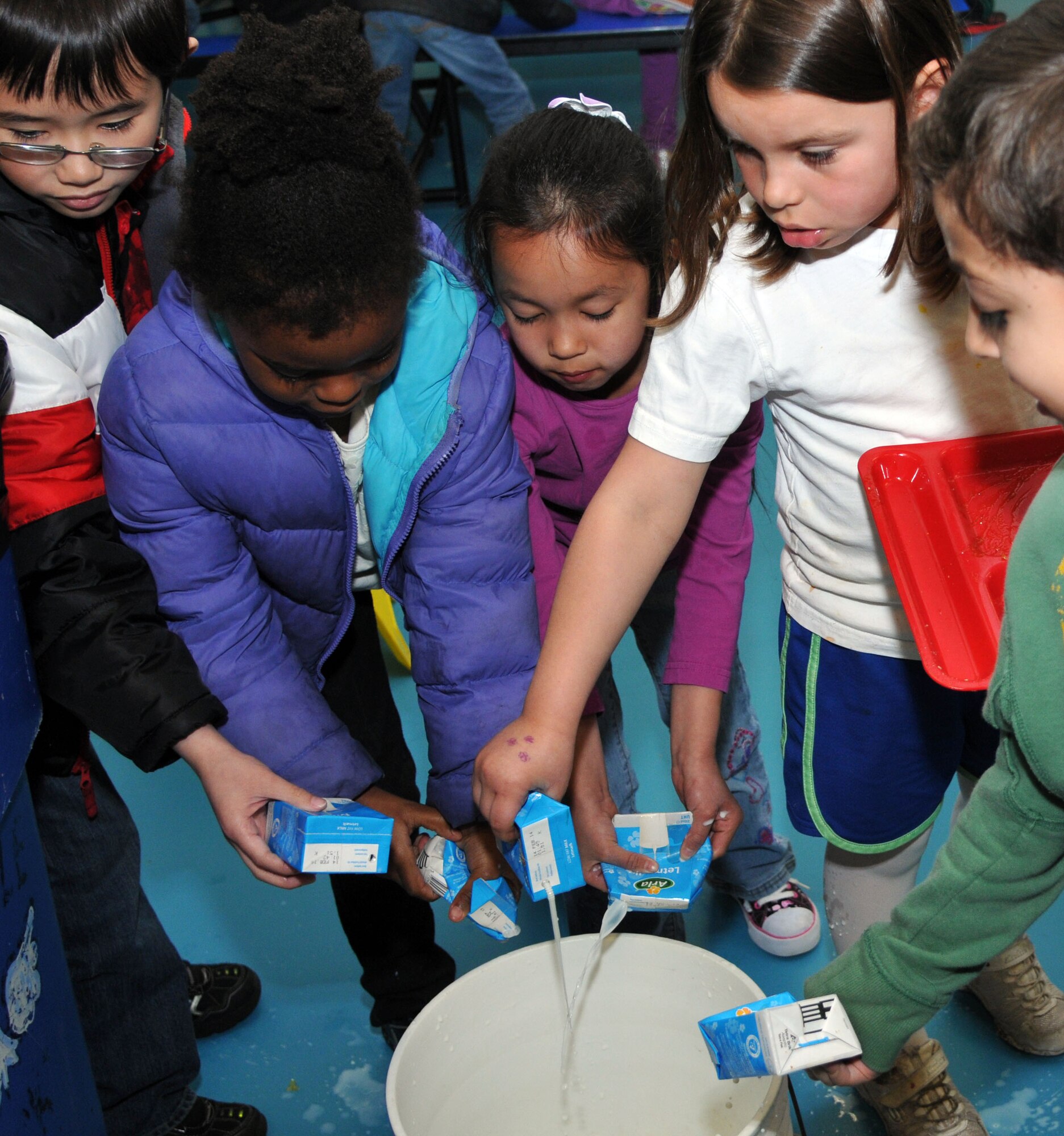 Children empty leftover milk into a pail before disposing of the cartons April 15, 2013, at Lakenheath Elementary School, RAF Lakenheath, England. April is Month of the Military Child because, just like their parents, military children serve too.  “We know that military children face many challenges unique to their situation, such as having a parent deployed for extended periods of time and moving frequently,” stated Lucille Sutherland, LES principle, in an email to parents. As a visible way to show support, Operation Military Kids encourages everyone to wear purple during the month of April. (U.S. Air Force photo by Airman 1st Class Kelsey Waters/Released)