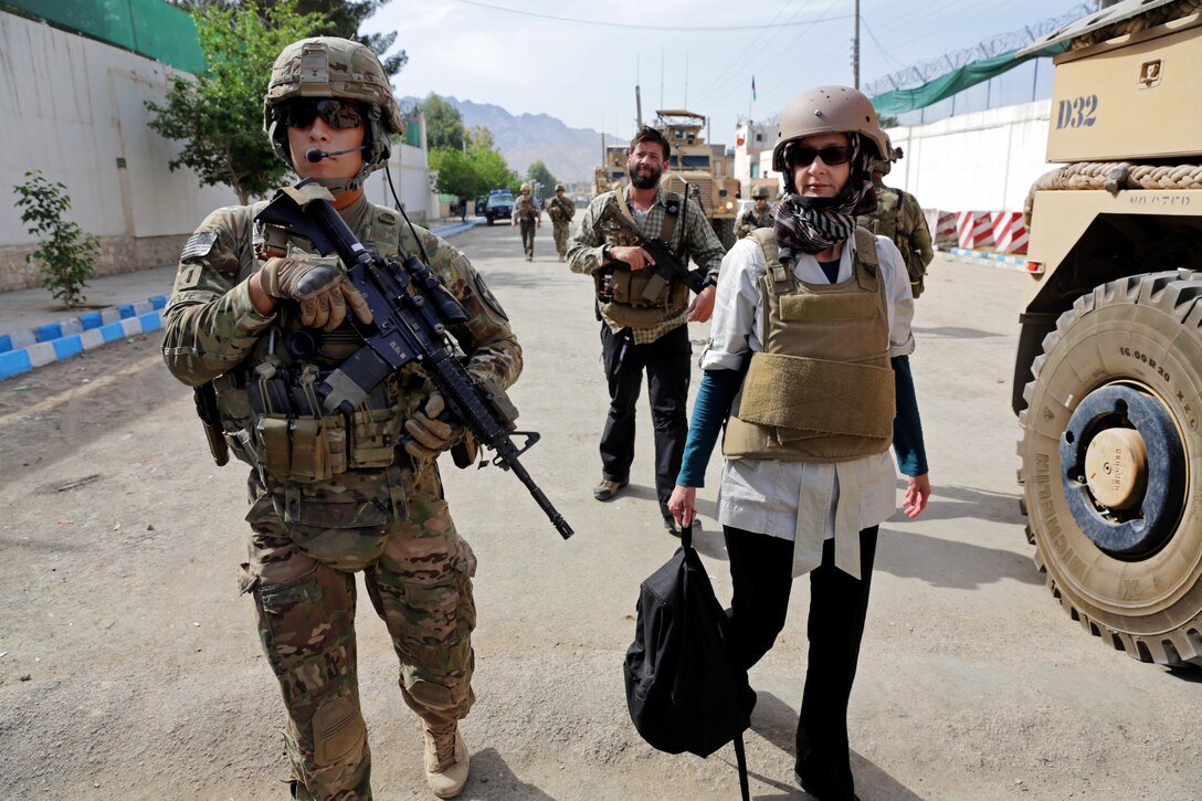 U.S. Army 1st Lt. Robert Wolfe, left, walks beside U.S. Consul General Jillian Burns upon arriving at the site of a meeting with the Farah provincial council at the governor's compound in Farah City, Afghanistan, April 11, 2013. Wolfe, a platoon leader, is assigned to Provincial Reconstruction Team Farah. The consul general and reconstruction team members met with the Farah provincial council and other leaders to express condolences for a recent terrorist attack in Farah City and to assess damage to government buildings.