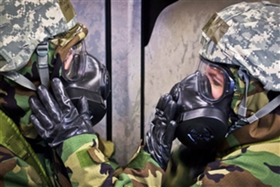U.S. Air Force Master Sgt. Jessica Sobczyk, left, and Tech. Sgt. Leah Rogers assist each other in securing their gas masks during an exercise at General Mitchell International Airport, Wis., April 13, 2013. The training exercise helps prepare airmen from the Wisconsin Air National Guard for operations in chemical, biological, radioactive and nuclear environments. Sobczyk and Rogers are assigned to the 128th Air Refueling Wing.