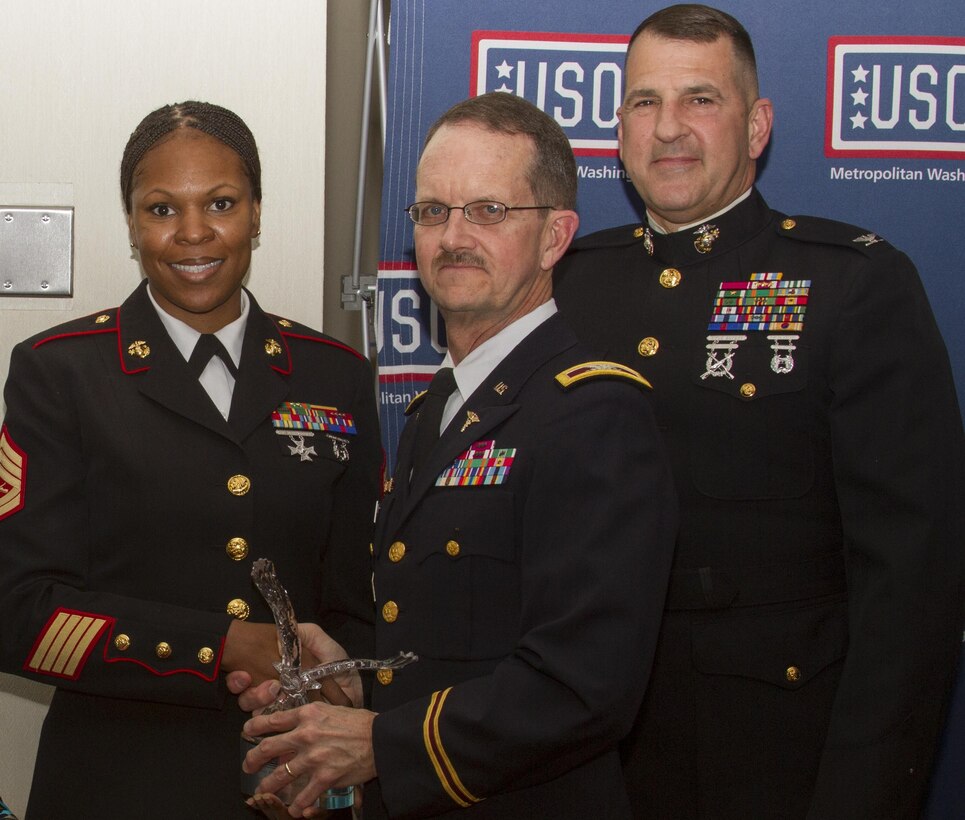 FORT BELVOIR, Va. – Gunnery Sgt. Tawanda Hanible, Diversity Operations Chief, Office of Diversity, Marine Corps Recruiting Command, receives the C. Haskell Small Award for volunteerism, during the USO of Metropolitan Washington Annual Celebration of Volunteers at the officer’s club, here, Saturday. Presenting the award is Army Col. Charles Callahan, Commander, Fort Belvoir Community Hospital. Hanible, a Chicago native, is the founder and chief executive officer of Operation Heroes Connect, a non-profit organization that provides at risk youth with positive role models through volunteer service members and veterans. Also pictured is Col. Robert G. Golden III, chief of staff, MCRC.
