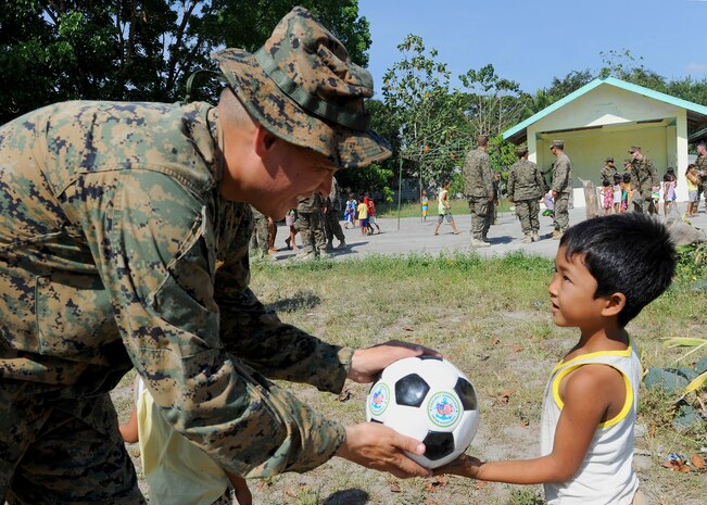 U.S. Navy Lt. Garrett Craig, a Colorado native and chaplain with Combat Logistics Regiment 35, 3rd Marine Logistics Group, III Marine Expeditionary Force, hands a Project Hand Clasp soccer ball to a Filipino student at Maruglo Elementary School in Crow Valley, Philippines, April 12 during ongoing community relations events at Balikatan 2013, an annual Philippine-U.S. bilateral exercise. Humanitarian assistance and training activities enable the Philippine and U.S. forces to build lasting relationships, train together and provide assistance in communities where the need is the greatest.