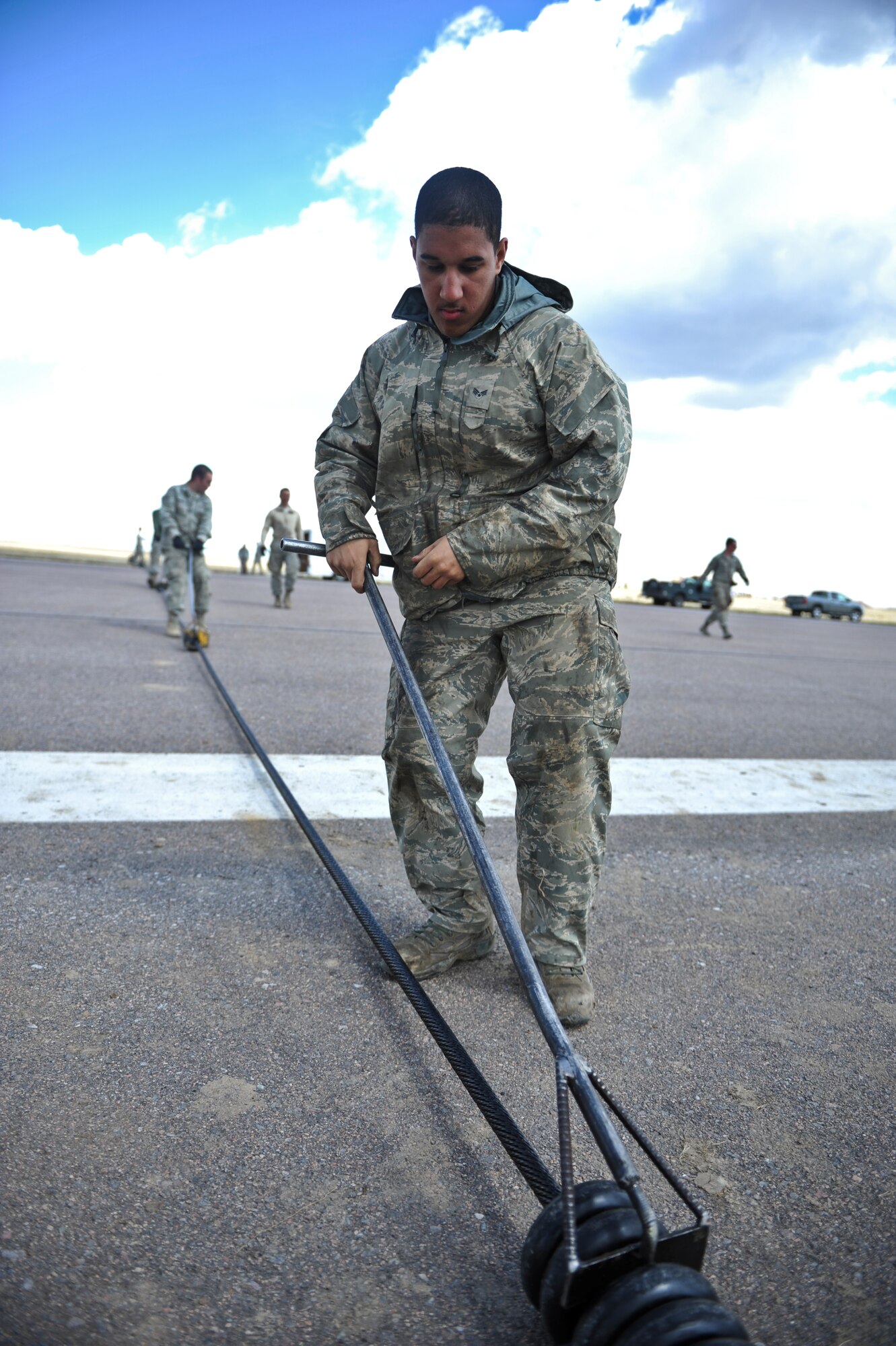 Senior Airman Taquan Kelley, 460th Civil Engineer Squadron power production journeyman, spreads out donut-like supports on a Barrier Arresting Kit-12 system April 12, 2013, on the flightline at Buckley Air Force Base, Colo. Kelley was one of several power production Airmen assisting in the assembly of the BAK-12 systems. (U.S. Air Force photo by Airman 1st Class Riley Johnson/Released) 