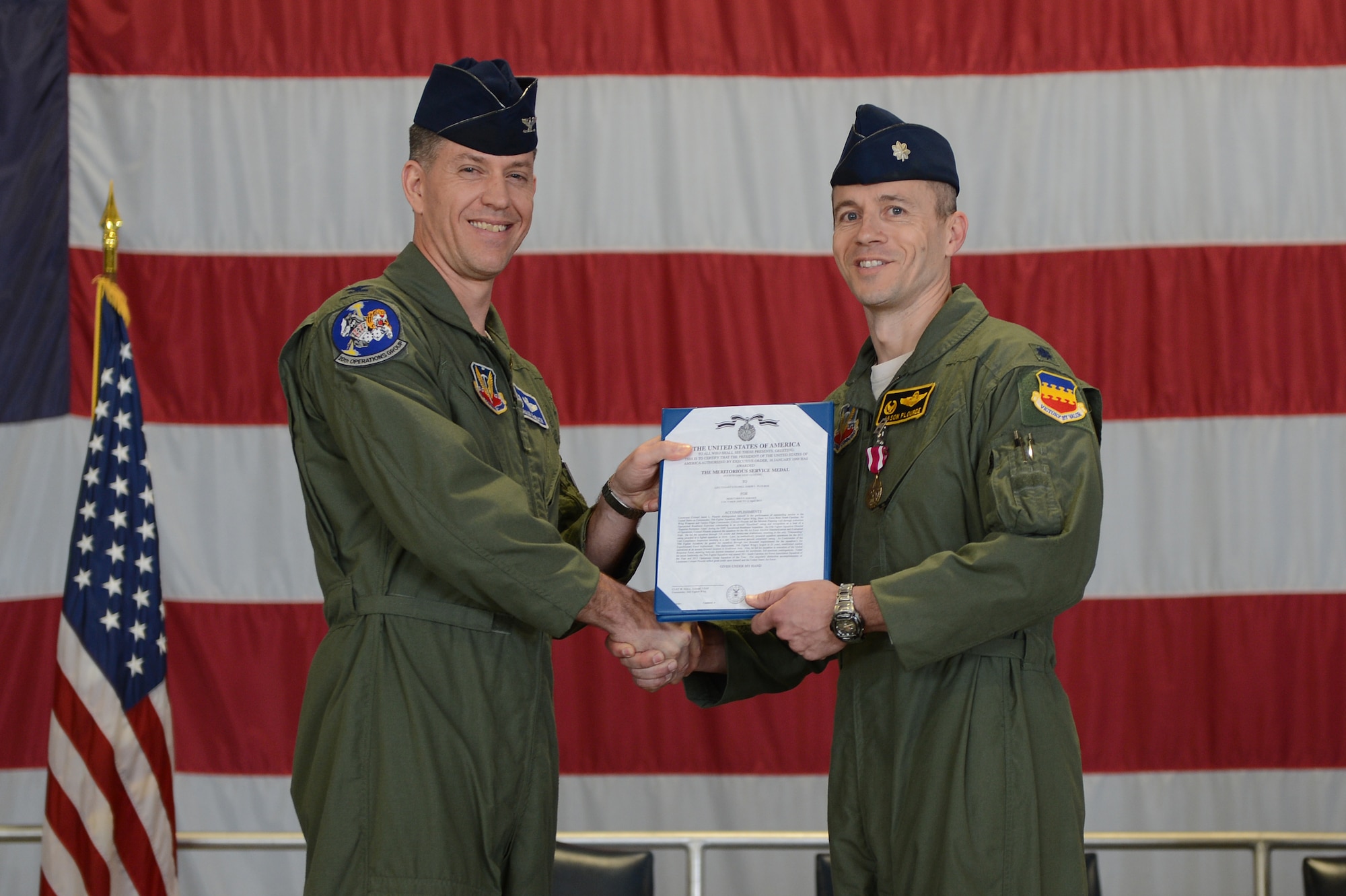 Col. Shaun McGrath (left), 20th Operations Group commander, presents Lt. Col. Jason Plourde, 79th Fighter Squadron (outgoing) commander with the Meritorious Service Medal for his actions in the line of duty during his change of command ceremony, Shaw Air Force Base, S.C., April 12, 2013. A Change of command is a military tradition that represents the transfer of responsibilities from the presiding official to a qualified selected official. (U.S. Air Force photo by Airman 1st Class Daniel Blackwell/released)