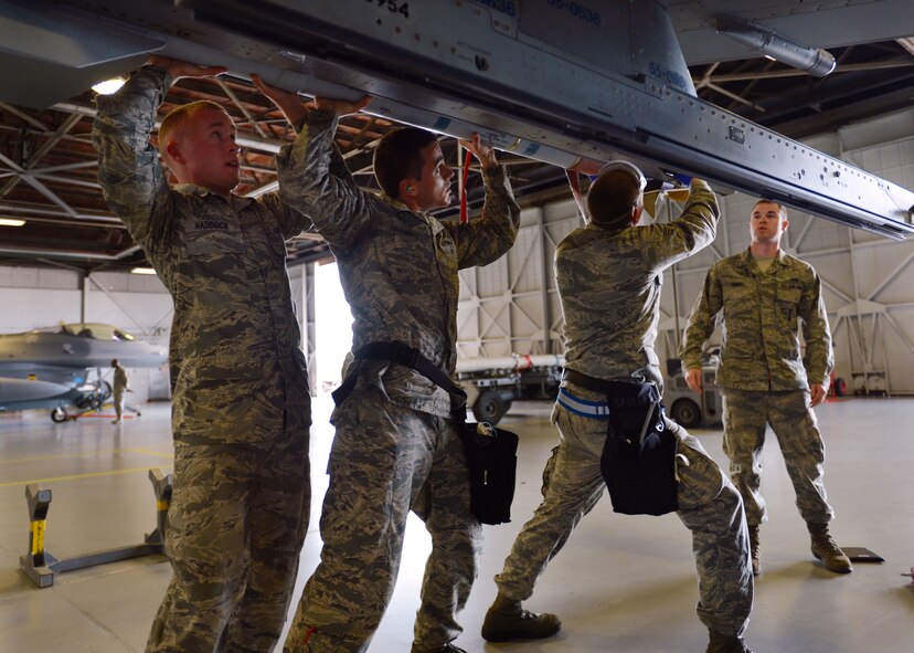 U.S. Air Force Senior Airman Dylan Haddock, 55th Aircraft Maintenance Unit ?Shooters? weapons load crew member, Staff Sgt. Richard Randall, 55th AMU weapons load crew chief, and Senior Airman Jacob Gibbons, 55th AMU weapons load crew member, attach an Air Intercept Missile-9LM to a F-16 Fighting Falcon at Shaw Air Force Base, S.C., April 12, 2013. The 55th AMU ?Shooters? and 79th AMU ?Tigers? competed against one another during the Weapons Load Crew of the Quarter competition. (U.S. Air Force photo by Senior Airman Tabatha Zarrella/Released)