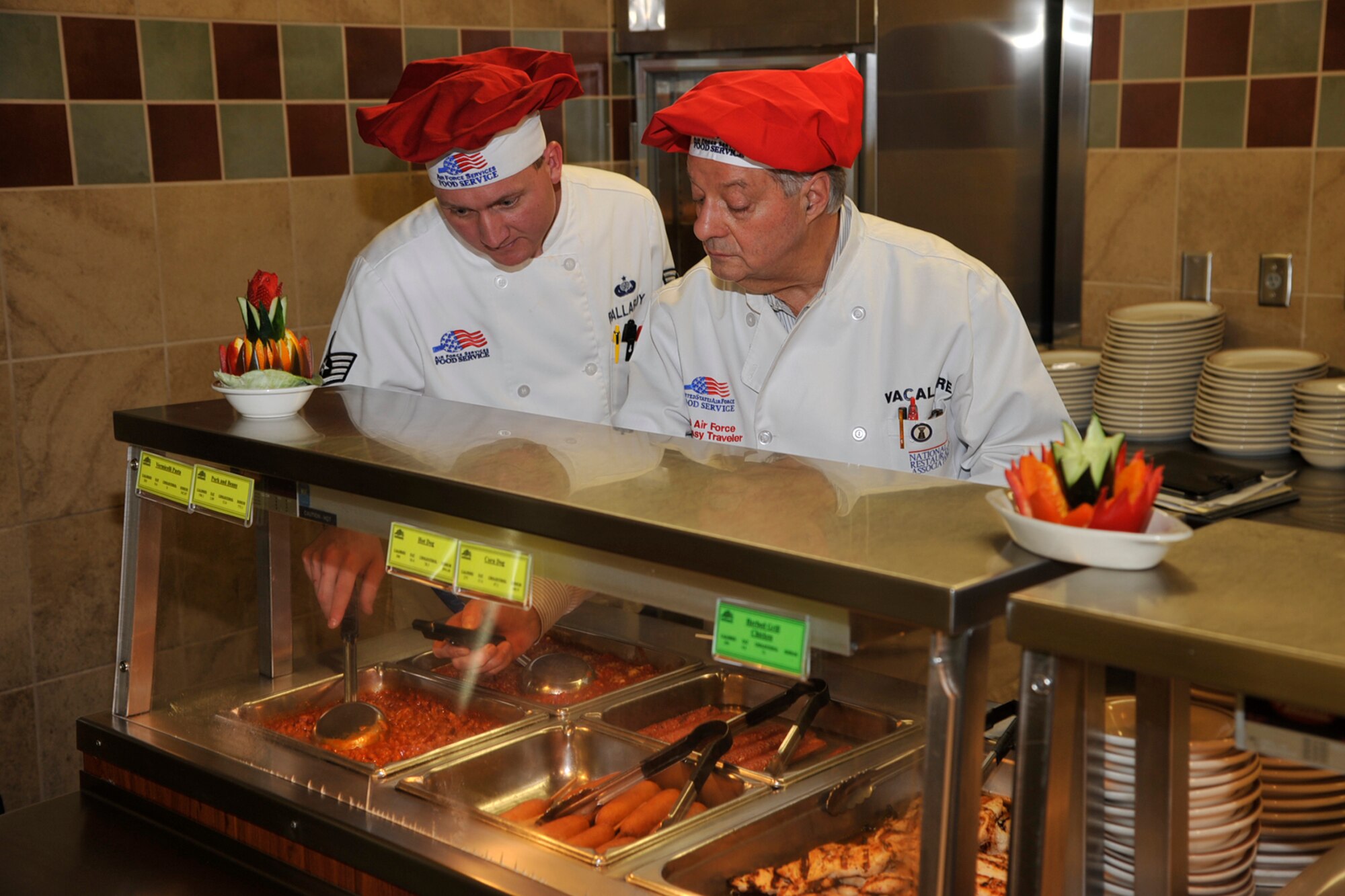 PETERSON AIR FORCE BASE, Colo. -- Staff Sgt. Joshua Pallardy (left), Aragon Dining Facility and Carmen Anthony Vacalebre, Hennessy Evaluation Team, inspect food at the Aragon Dining Facility April 8. The evaluation was to ensure that food is properly cooked and maintained for Peterson AFB Airmen. The Aragon was named best in Air Force Space Command and the John L. Hennessy award recognizes the top food service operation in the Air Force. (U.S. Air Force photo/Rob Lingley)