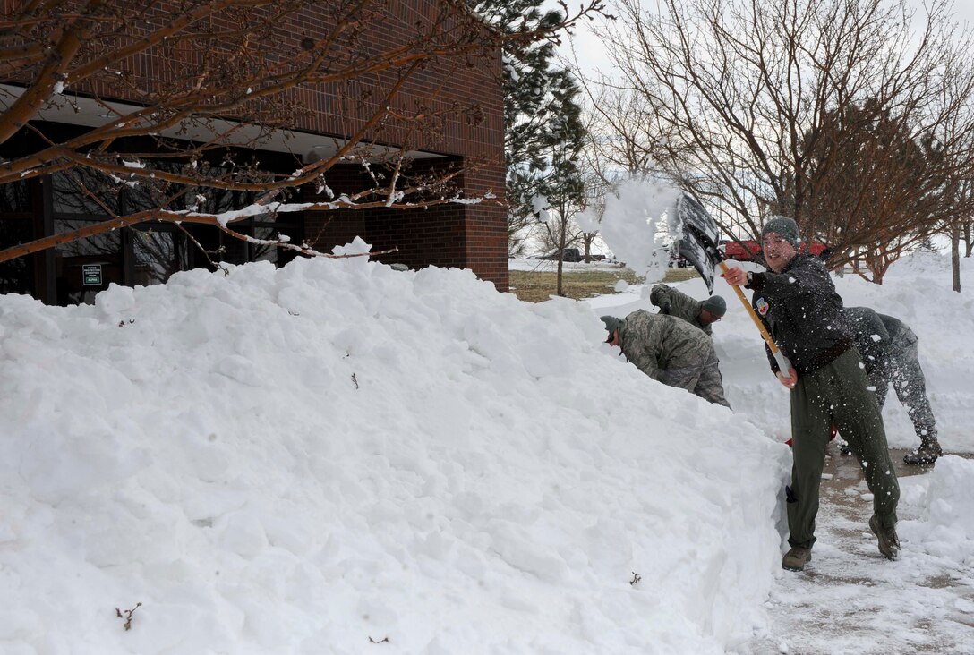 Capt. David Smith, 28th Operation Support Squadron intelligence weapons and tactics flight commander, shovels snow from the sidewalk outside the 28th Bomb Wing Headquarters building at Ellsworth Air Force Base, S.D., April 11, 2013. Base operations were significantly reduced for two days due to a heavy snowstorm that hit Box Elder and the surrounding areas earlier this month. (U.S. Air Force photo by Airman 1st Class Anania Tekurio/Released)