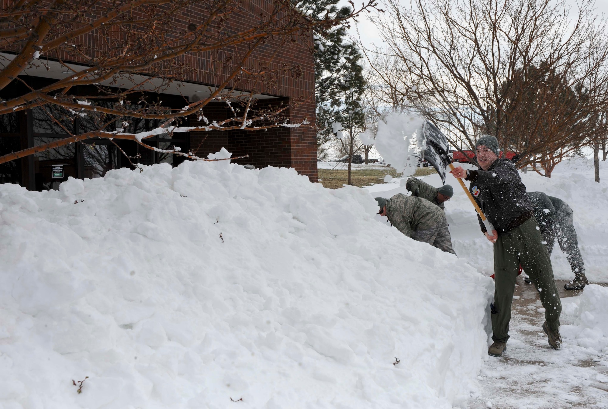 Capt. David Smith, 28th Operation Support Squadron intelligence weapons and tactics flight commander, shovels snow from the sidewalk outside the 28th Bomb Wing Headquarters building at Ellsworth Air Force Base, S.D., April 11, 2013. Base operations were significantly reduced for two days due to a heavy snowstorm that hit Box Elder and the surrounding areas earlier this month. (U.S. Air Force photo by Airman 1st Class Anania Tekurio/Released)