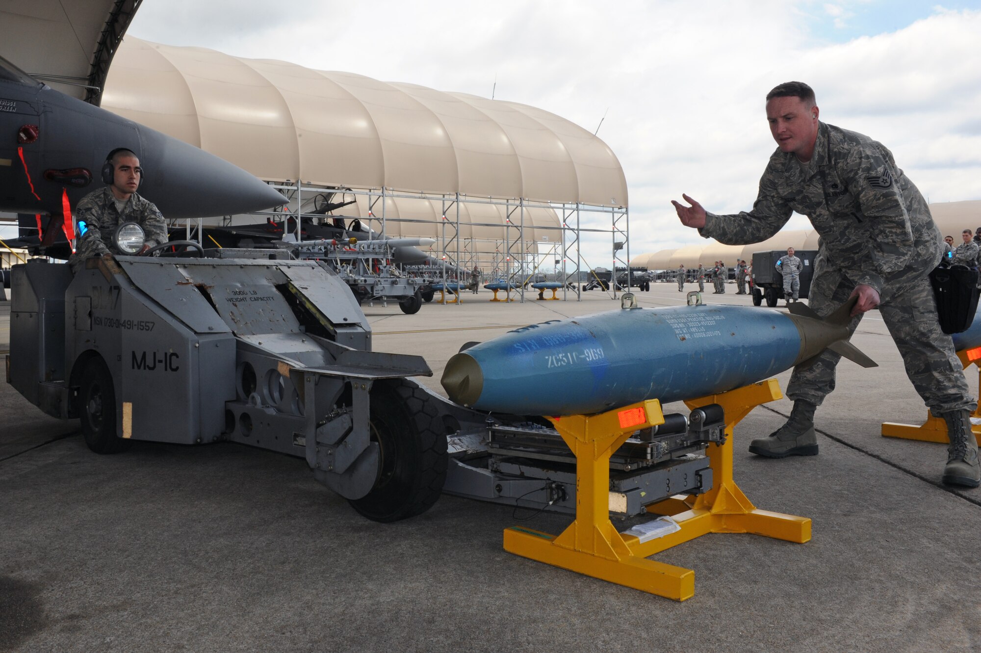 U.S. Air Force Staff Sgt. David Budine, right, 4th Aircraft Maintenance Squadron weapons load crew chief, guides Airman 1st Class Michael Meza, 4th AMXS weapons load crew member, through a BDU-50 munition installation on an F-15E Strike Eagle during a load crew competition on Seymour Johnson Air Force Base, N.C., April 5, 2013. Airmen from the 4th AMXS represented their respective aircraft maintenance units in the competition to earn bragging rights across the flight line. (U.S. Air Force photo by Airman 1st Class John Nieves Camacho/Released)