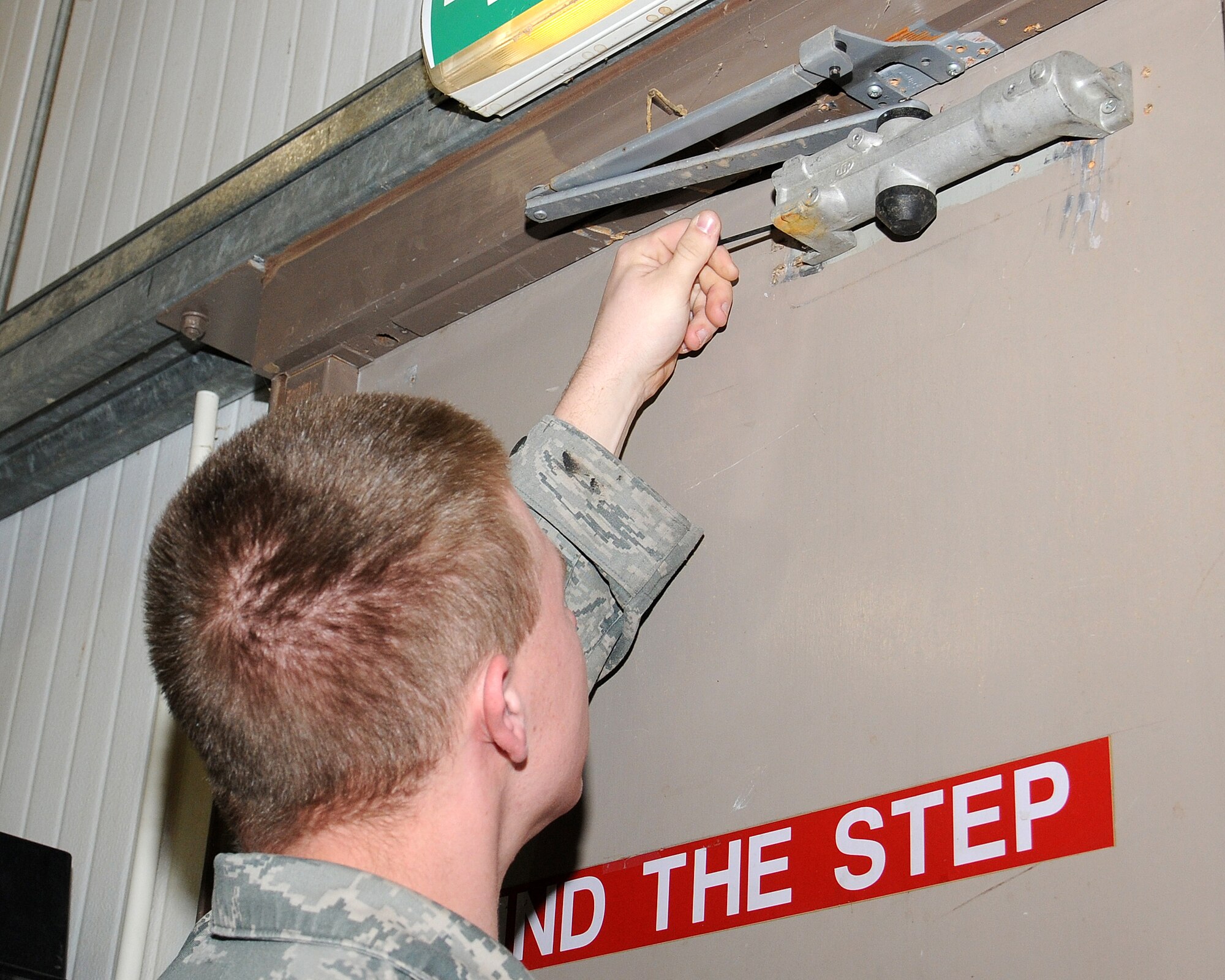 Airman 1st Class Scott Haeseler, 100th Civil Engineer Squadron structural journeyman from Mystic, Conn., adjusts a surface-mounted hydraulic door closure April 15, 2013, at RAF Mildenhall, England. The shop has 10 military personnel and 20 civilians working to maintain the buildings on base, ensuring they are safe and secure. (U.S. Air Force photo by Gina Randall/Released)