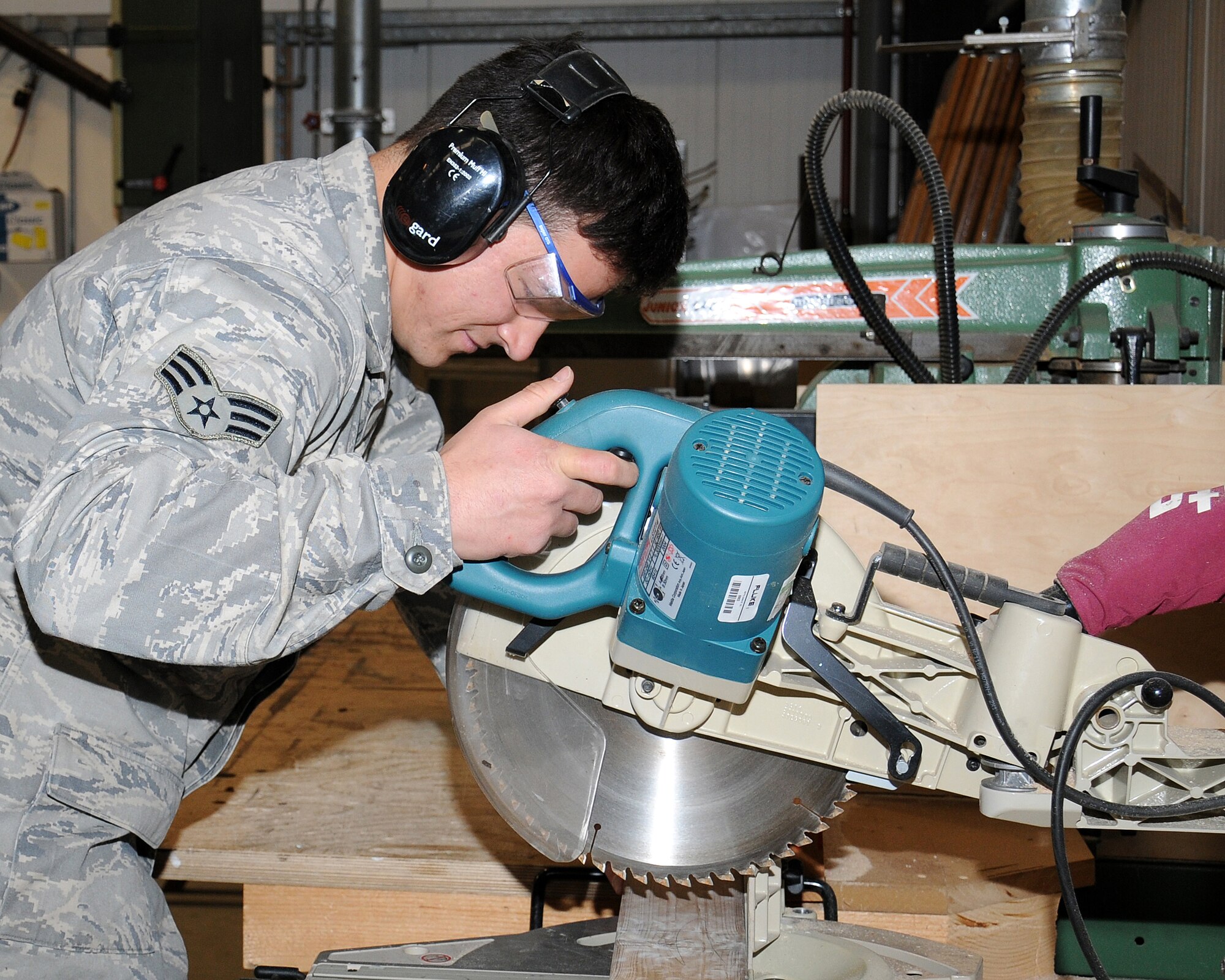 Senior Airman Vincente Andrade, 100th Civil Engineer Squadron structural journeyman from Emeryville, Calif., cuts a piece of wood April 15, 2013, at RAF Mildenhall, England. The structures shop maintains all the doors, windows, framing walls and woodwork on base. (U.S. Air Force photo by Gina Randall/Released)