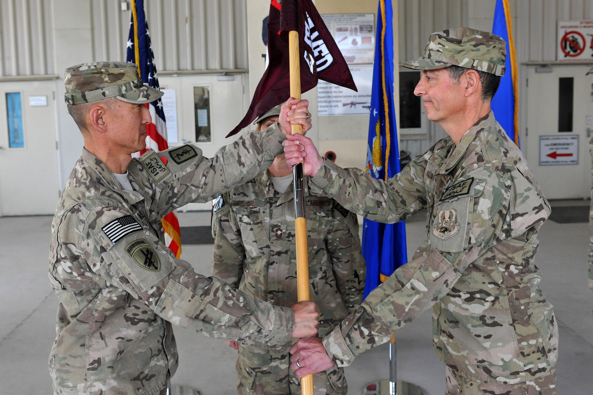 Col. Koji Nishimura, Task Force Medical-Afghanistan commander, passes the 455th Task Force Medical East guidon to Col. Dominic DeFrancis during a Change of Command ceremony on Bagram Airfield, Afghanistan, April 12, 2013.  DeFrancis will provide command and control for all medical support above brigade level for U.S. and Coalition forces across Regional Command East/North in Afghanistan. (U.S. Air Force photo/Senior Airman Chris Willis)