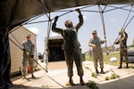 (Left-right) Army Sgt. Marc Jones, Army Staff Sgt. Robert Ribeiro, Staff Sgt. Gonzalo Roman and Master Sgt. Mark Martinez set up a base-X tent, part of the Joint Incident Communications Capability (JICC) that will provide video teleconference, satellite and cellular communications next to the Emergency Operations Center at Brooks City-Base in San Antonio July 22. The Texas Army National Guard is part of the Standing Joint Interagency Task Force-Texas at Camp Mabry, Texas. Sergeants Jones and Ribeiro are stationed at Bee Caves Armory, Austin, Texas. Sergeants Roman and Martinez are from the Air National Guard's 149th Communications Flight at Lackland Air Force Base, Texas. Once completed the JICC will provide 2000 sq. ft. of portable or tented floor space on the lawns in front of the EOC. (U.S. Air Force photo/) 