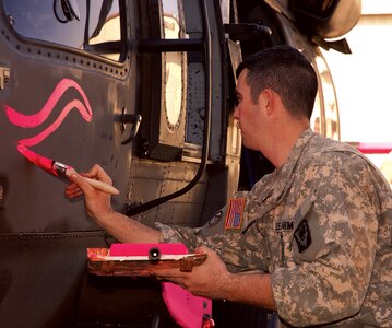 Sgt. Jim Irby of Mobile, a Black Hawk crew chief, puts distinctive markings on a Alabama Army Guard UH-60 helicopter while fighting forest fires in California.