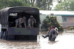 Pvt. Mark Rivera, A Co., 72nd Infantry Brigade, and Pvt. 1st Class Joseph Davora, A Co., 1-41 Infantry Regiment, carry a woman stranded by flood waters to a waiting truck, where Pvt. John Paul Borrego and Pvt. 1st Class Christopher Culbelier, both from Headquarters and Headquarters Company, 72nd Inf. Bde. wait to lift her in. 