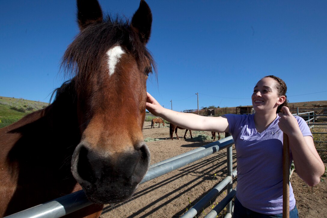 Lance Cpl. Kathryn Howard pets a horse during the Single Marine Program’s volunteer event at the Stepp Stables here April 17. Howard is a photographer with Headquarters and Support Battalion’s Combat Camera here.