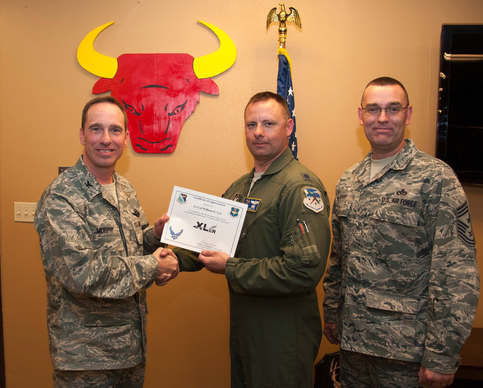 Lt. Col. William Lee, 96th Flying Training Squadron functional check flight chief, poses with Col. Tom Murphy, 47th Flying Training Wing commander, and Chief Master Sgt. Garry Berry, 47th FTW command chief, after being presented the XLer of the week award at Laughlin Air Force Base, Texas, March 26, 2013. The XLer is a weekly award chosen by wing leadership and given to those who consistently make outstanding contributions to Laughlin and their unit. (U.S. Air Force photo/Airman 1st Class John D. Partlow)