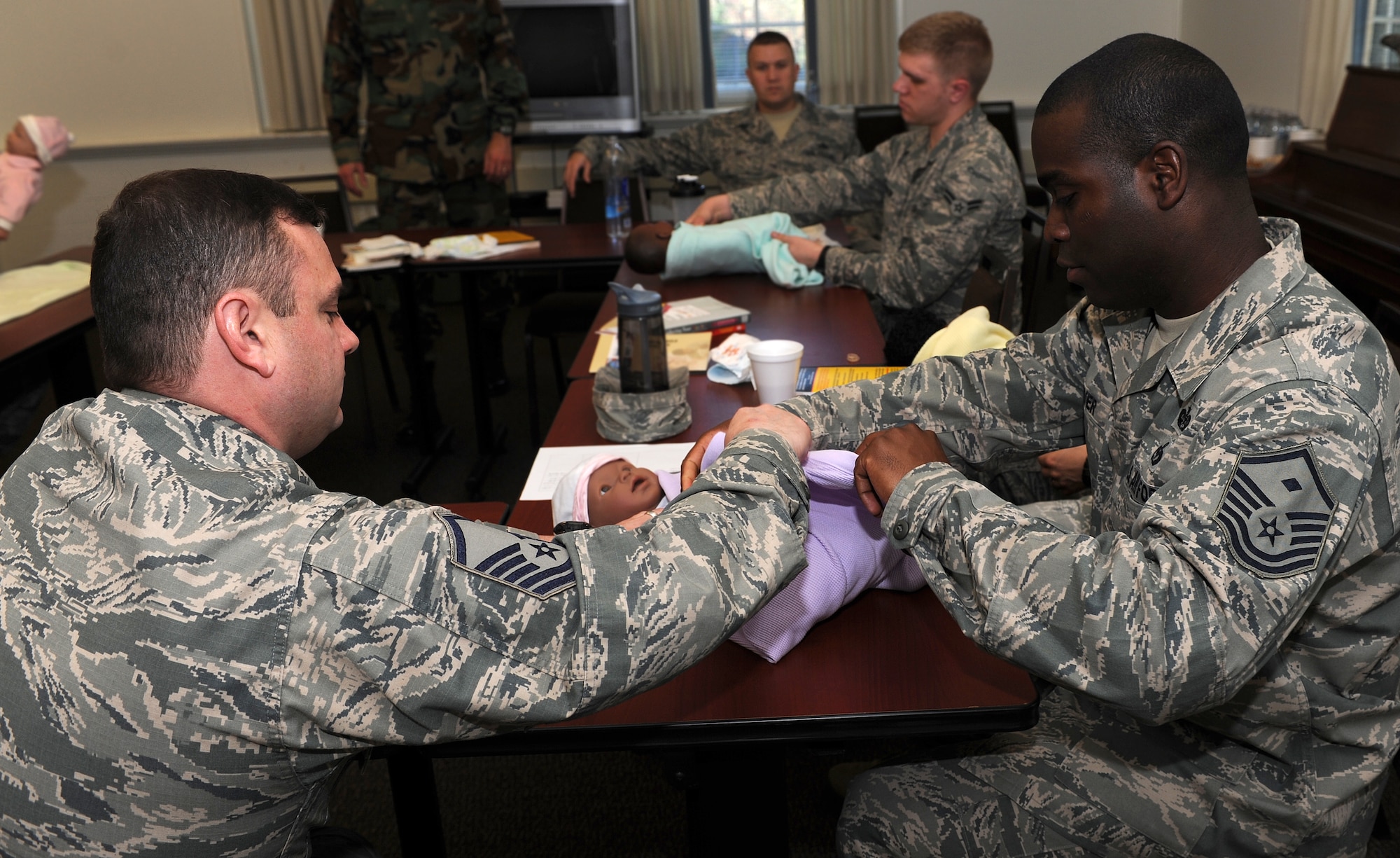 U.S. Air Force Master Sgt. Byron Rauch, father of three and currently expecting his fourth daughter, assists Master Sgt. Ralph Oliver, 45th Intelligence Squadron first sergeant, and soon to be first-time father, in swaddling a doll representing a newborn child during a New Fathers Workshop at Langley Air Force Base, Va. April 11, 2013. The workshop was provided as a way to help prepare new and expecting fathers for their journey into fatherhood. (U.S. Air Force photo by Senior Airman Teresa Aber/Released)