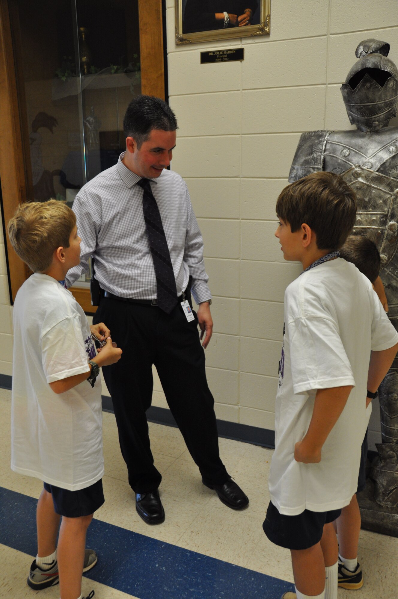 Dr. Richard Rogers, Matt Arthur Elementary principal, speaks to the Johnson brothers while passing through the halls of the school during Purple Up day Friday, April 12, 2013. Mike Johnson is the youngest of the three brothers and said the best part of being a military kid is the traveling. He is five-years-old and has lived in four states. April is the month of the Military Child which recognizes their service, sacrifice and the hardships they face (U.S. Air Force photo by Chandra Brown).