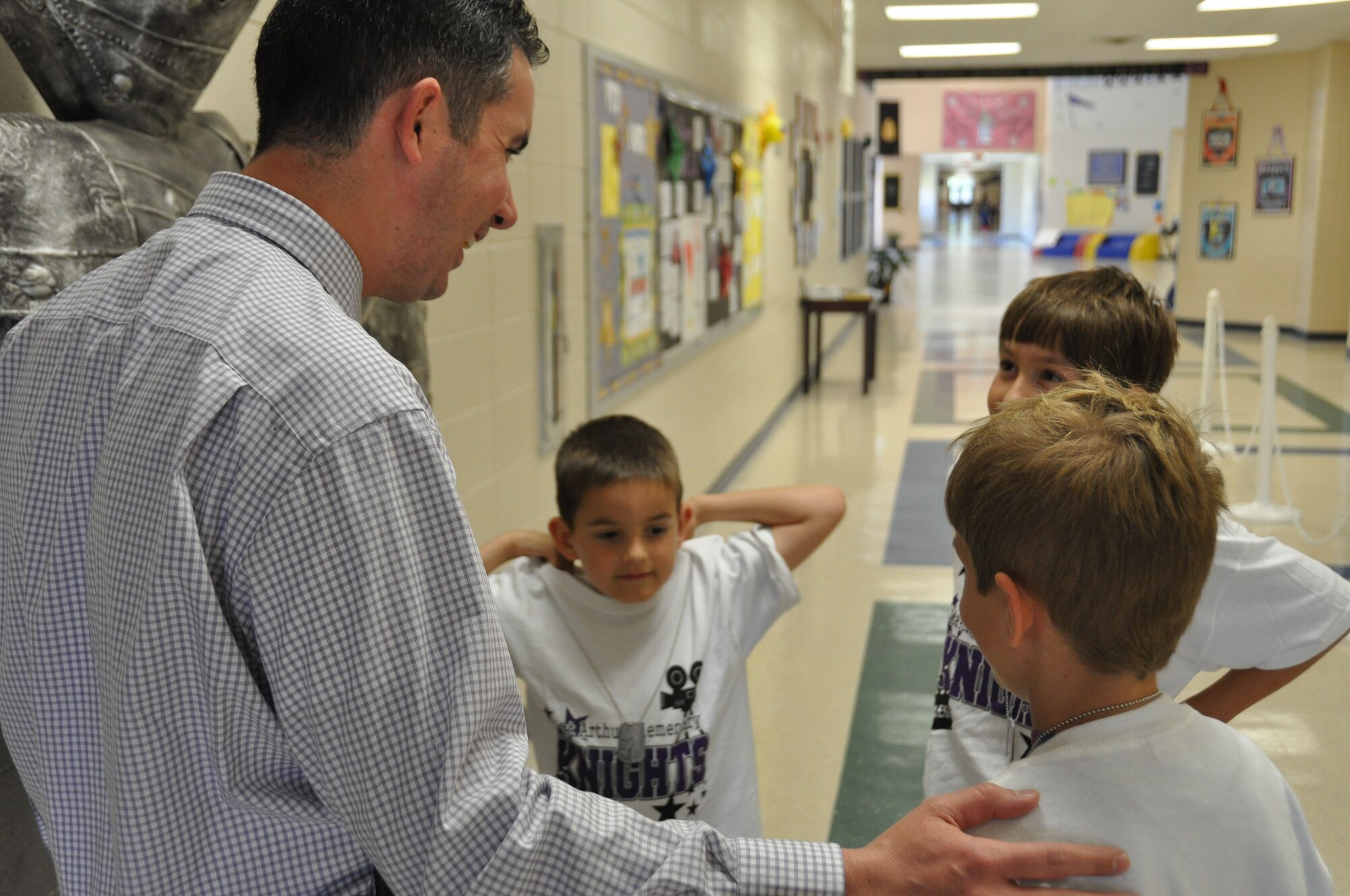 Dr. Richard Rogers, Matt Arthur Elementary principal, speaks to the Johnson brothers while passing through the halls of the school during Purple Up day Friday, April 12, 2013. Mike Johnson is the youngest of the three brothers and said the best part of being a military kid is the traveling. He is five-years-old and has lived in four states. April is the month of the Military Child which recognizes their service, sacrifice and the hardships they face (U.S. Air Force photo by Chandra Brown).