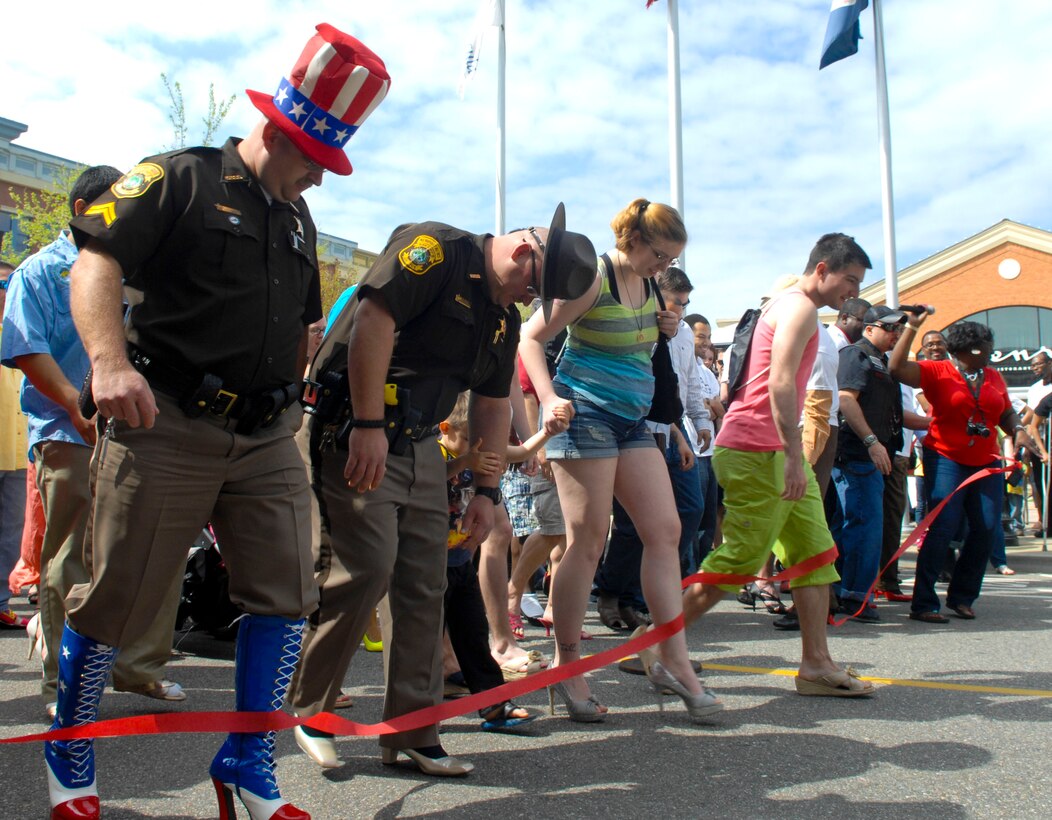 Walkers break the red tape, kicking of the “Walk a Mile in Her Shoes” event in Hampton, Va., April 13, 2013. Participants strut their stuff, donning high heels, for one mile to help raise awareness about sexual violence. (U.S. Air Force photo by Airman 1st Class Austin Harvill/Released)