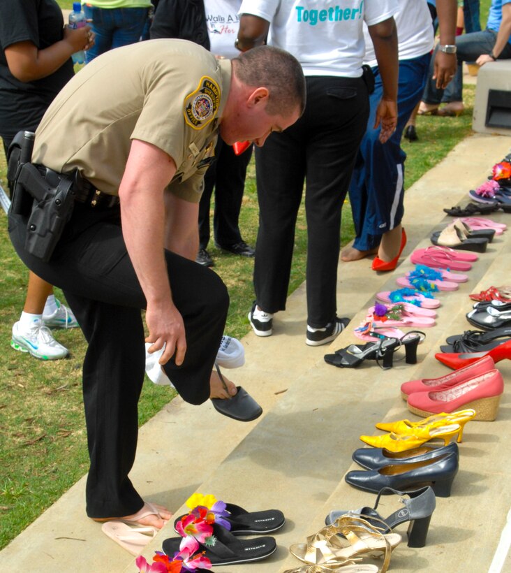 A Hampton Sherriff’s Office policeman tries on a pair of heels before participating in the annual “Walk a Mile in Her Shoes” event in Hampton, Va., April 13, 2013. Individuals from all walks of life showed up to lend their support to the event, which illustrated how sexual violence affects everyone. (U.S. Air Force photo by Airman 1st Class Austin Harvill/Released)