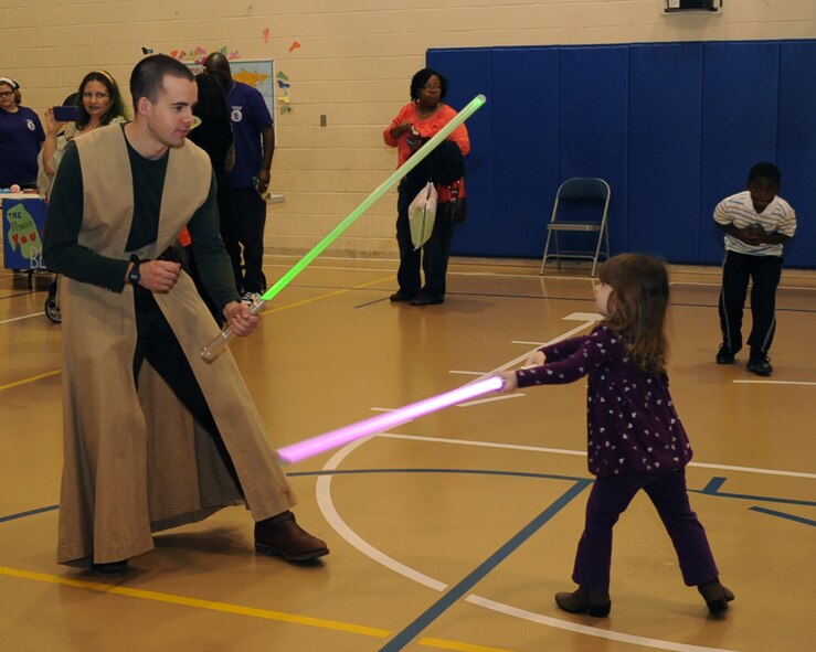 A volunteer from the Star Wars Society of Shreveport/Bossier has a light saber fight with Kara Price, daughter of Maj. Adam Price, during the Books on Bases event at the Youth Center on Barksdale Air Force Base, La., April 13, 2013. Books on Bases was created by Blue Star Families to positively impact the lives of military children through the power of reading. (U.S. Air Force photo/Senior Airman Sean Martin)