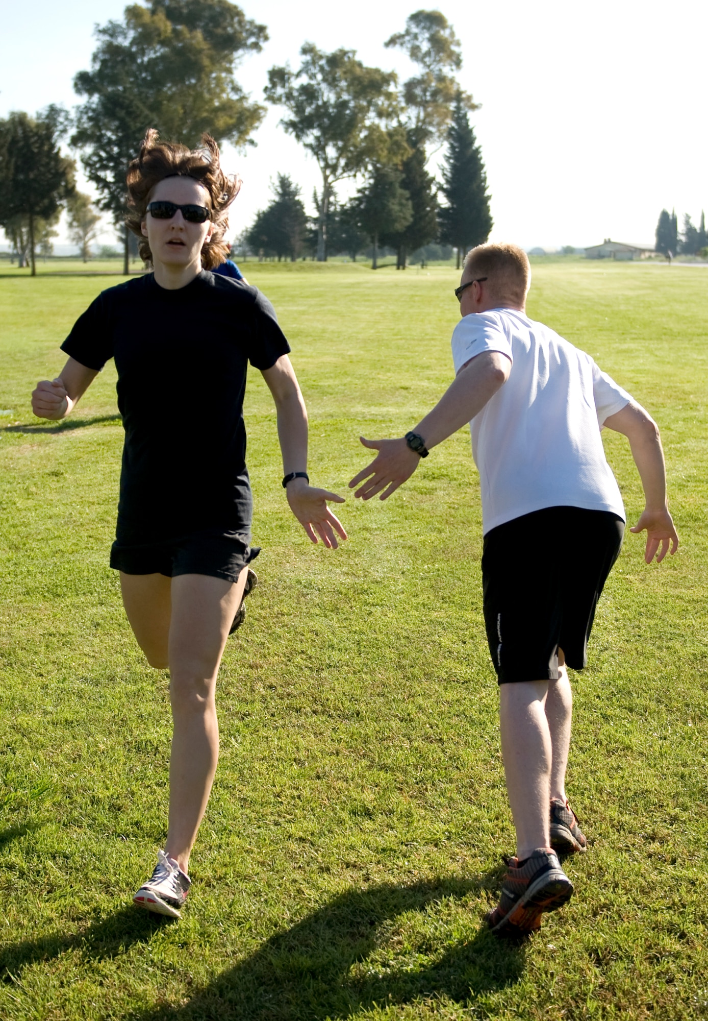 Capt. Tenille Woodward, 39th Air Base Wing sexual assault response coordinator competing with team “CGO 1” slaps the hand of her team mate  1st Lt. Nathan Thomsen, 39th Readiness and Emergency Management flight commander, as a sign for him to run during a cross-country relay race April 13, 2013, at the golf course on Incirlik Air Base, Turkey. Seventeen teams competed in the 4.5-mile relay. (U.S. Air Force photo by Senior Airman Daniel Phelps/Released)