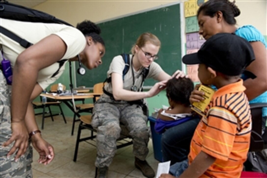U.S. Air Force Capt. Rebecca Slogic, center, and Capt. Chauncey Tarrant, left, examine a child’s head in Cerro Plata, Panama, on April 15, 2013.  The pediatricians are deployed from the San Antonio, Texas, Military Medical Center to Panama as part of Beyond the Horizon 2013, a joint and combined field training humanitarian exercise. The medical readiness portion provides much-needed health care services to some communities.  