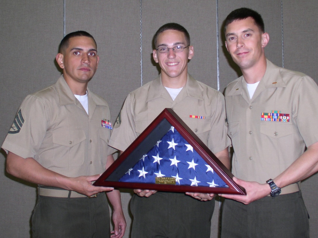Staff Sgt. Samuel Cerritos, platoon sergeant, and 2nd Lt. Lance Donald, platoon commander, present Lance Cpl. Cory Wolf, gunner, a flag at the Carteret County Chamber of Commerce Military Affairs Committee Service Person of the Quarter dinner April 12.  All three Marines are with 2nd Low Altitude Air Defense Battalion.     