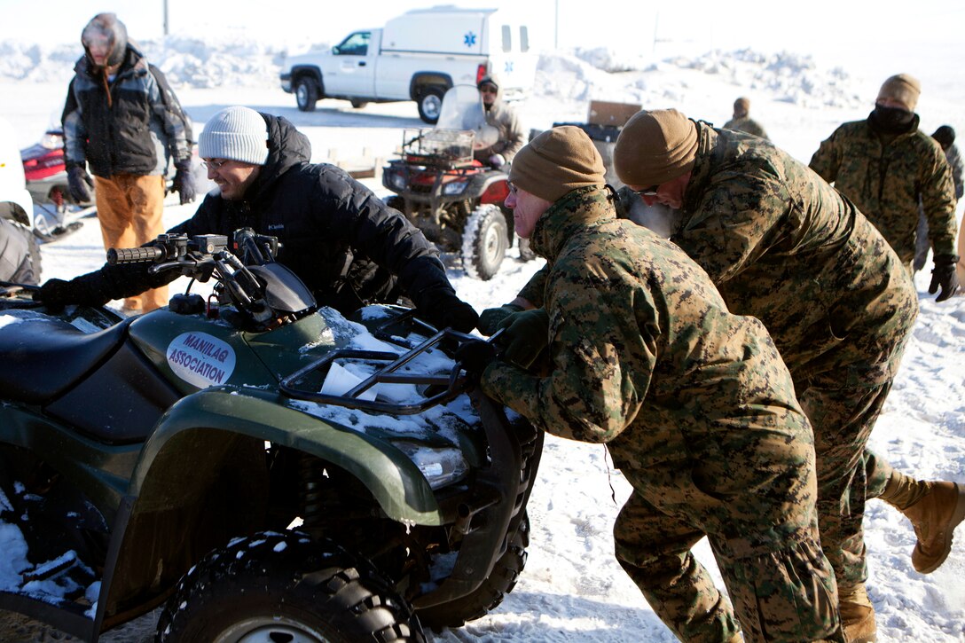 Brig. Gen. Roger R. Machut, the commanding general of 4th Marine Logistics Group, and Sgt. Maj. Richard Lewallen, the 4th MLG sergeant major, help locals push an all-terrain vehicle stuck in snow here, April 15. The ATV was hauling medical supplies unloaded from a National Guard UH-60 Black Hawk helicopter to this rural Alaskan town, where service members taking part in Innovative Readiness Training Arctic Care 2013 would provide medical, dental, and veterinary care. IRT Arctic Care is a multi-service humanitarian and training program focusing on enhancing the interoperability and capacity of U.S. forces in peacetime support operations, humanitarian assistance and disaster relief. The exercise is primarily a Reserve effort with Marine Forces Reserve taking the lead and receiving logistical and medical support from the National Guard, Army Reserve, Navy Reserve and Air Force Reserve. 