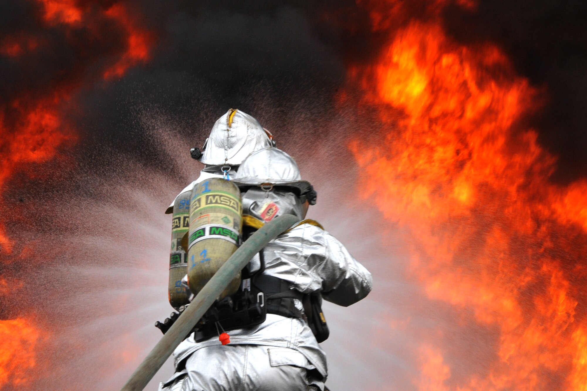 Staff Sgts. Christopher Haenelt, front, and Jason Tyson, 51st Civil Engineer Squadron fire and emergency services flight firefighters, perform a fire extinguishment during a jet-fuel fire training exercise at Camp Humphreys, Republic of Korea, April 17, 2013. This training allows firefighters to practice under conditions that could be encountered during realistic scenarios such as an aircraft crash. (U.S. Air Force photo/Senior Airman Alexis Siekert)