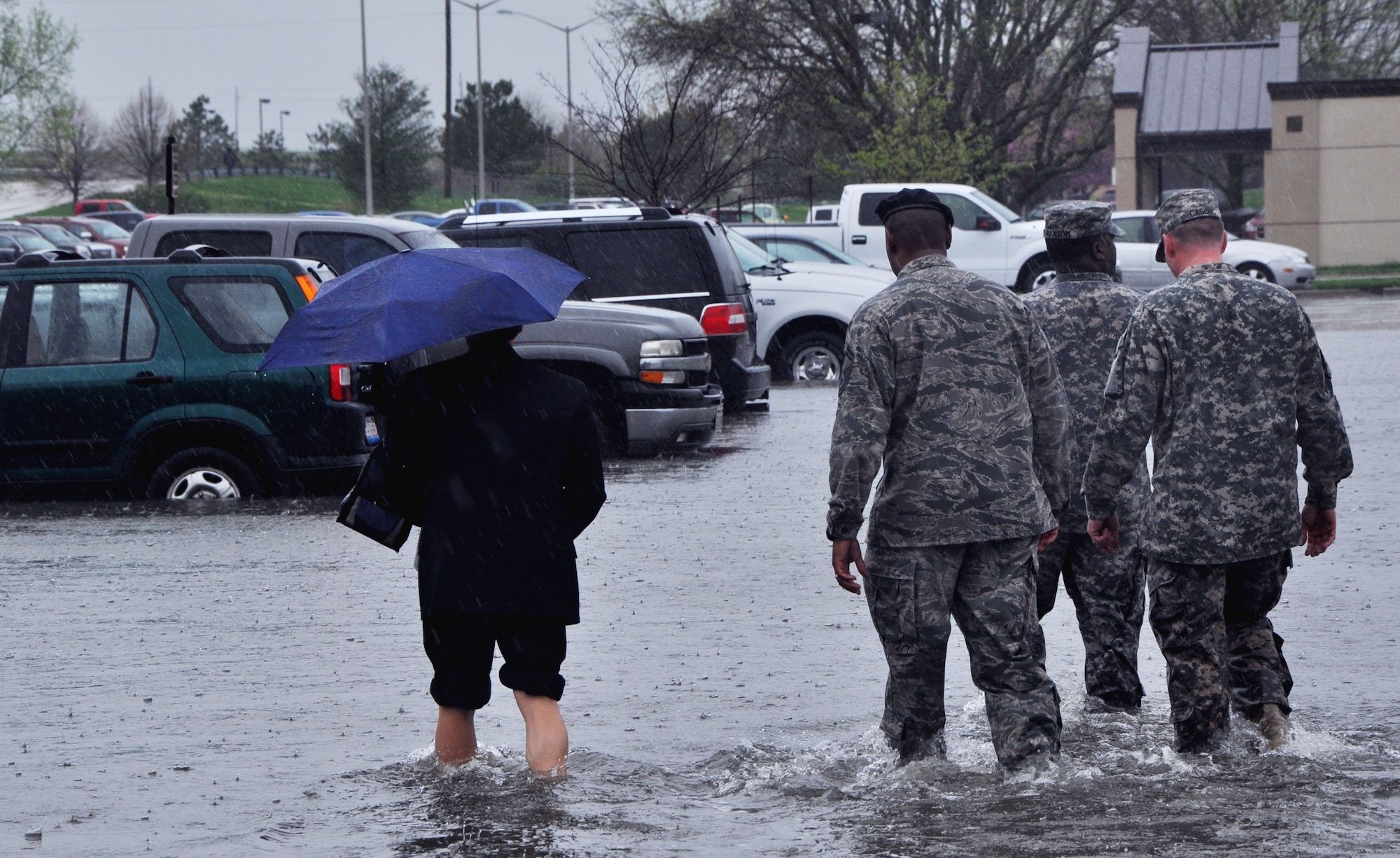 Servicemembers help a civilian to her car at Scott April 18, 2013 after rain dumped 5.2 inches on the base, causing floods and damage to vehicles and buildings. Throughout the day, servicemembers helped move cars from the flooded areas, while security forces members helped people exit the base and civil engineers assessed damage. (U.S. Air Force photo/Airman Megan Friedl)