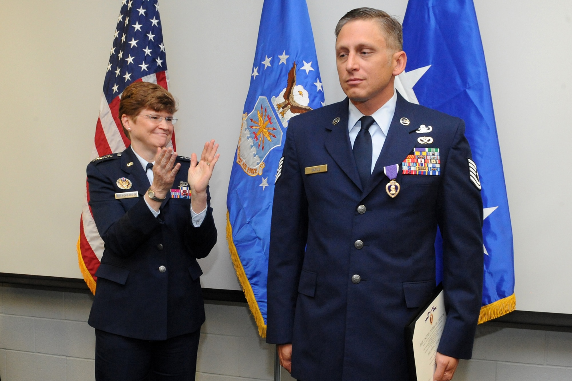 Tech. Sgt. Devin L. Datus, 775th Civil Engineer Squadron Explosive Ordnance Disposal technician, reflects as Gen. Janet C. Wolfenbarger, Air Force Materiel Command commander, applauds him after presenting him with the Purple Heart during a ceremony she officiated April 18. Datus was injured by an improvised explosive device while conducting route clearance operations in Helmand Province, Afghanistan, in July 2010. (U.S. Air Force photo/Alex R.Lloyd)