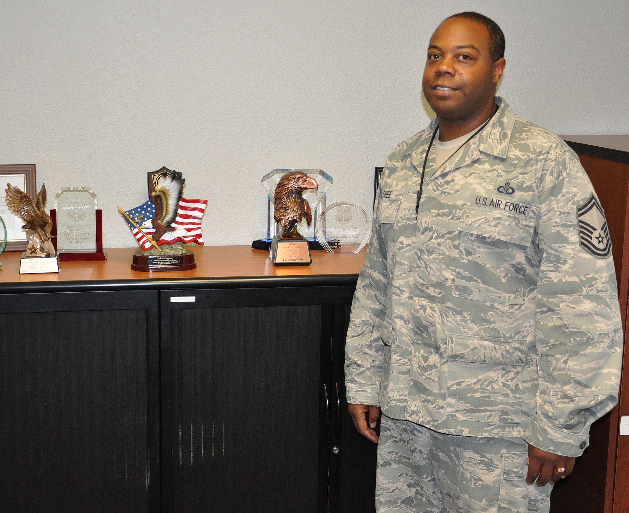 SMSgt Semaj McGhee stands in front of some of the awards presented to the Beale Command Post througout the years. Since 2010 this command post has won 17 individual and team awards and 4 MAJCOM level awards. (U.S. Air Force Photo/SrA Adam Hamar)