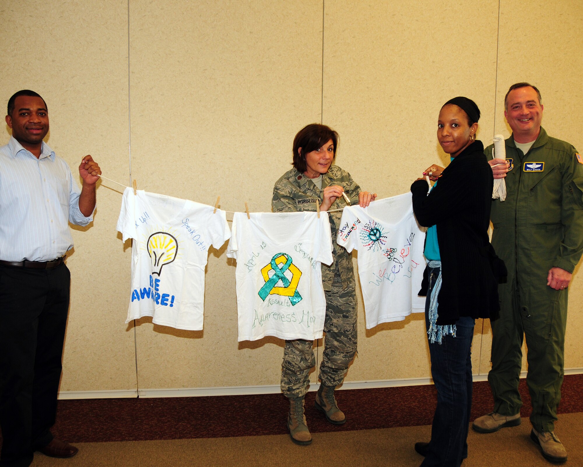 Mr. Jimmie Frost, 914th Airlift Wing Contract Specialist (left) and Col. Walter Gordon, 914th AW Vice Commander (right) hold the clothesline for Maj. Andrea Pitruzzella, 914th AW Public Affairs Officer and Ms. Nikki Slaughter, 914th AW Sexual Assault Response Coordinator during a Clothesline Project Event at the Niagara Falls Air Reserve Station on April 18, 2013. This national annual event encouraged base personnel and their dependants to decorate T-shirts or a pair of jeans with a message demonstrating their pledge to bring an end to Sexual Assault and Domestic Violence. (U.S. Air Force photo by Peter Borys)