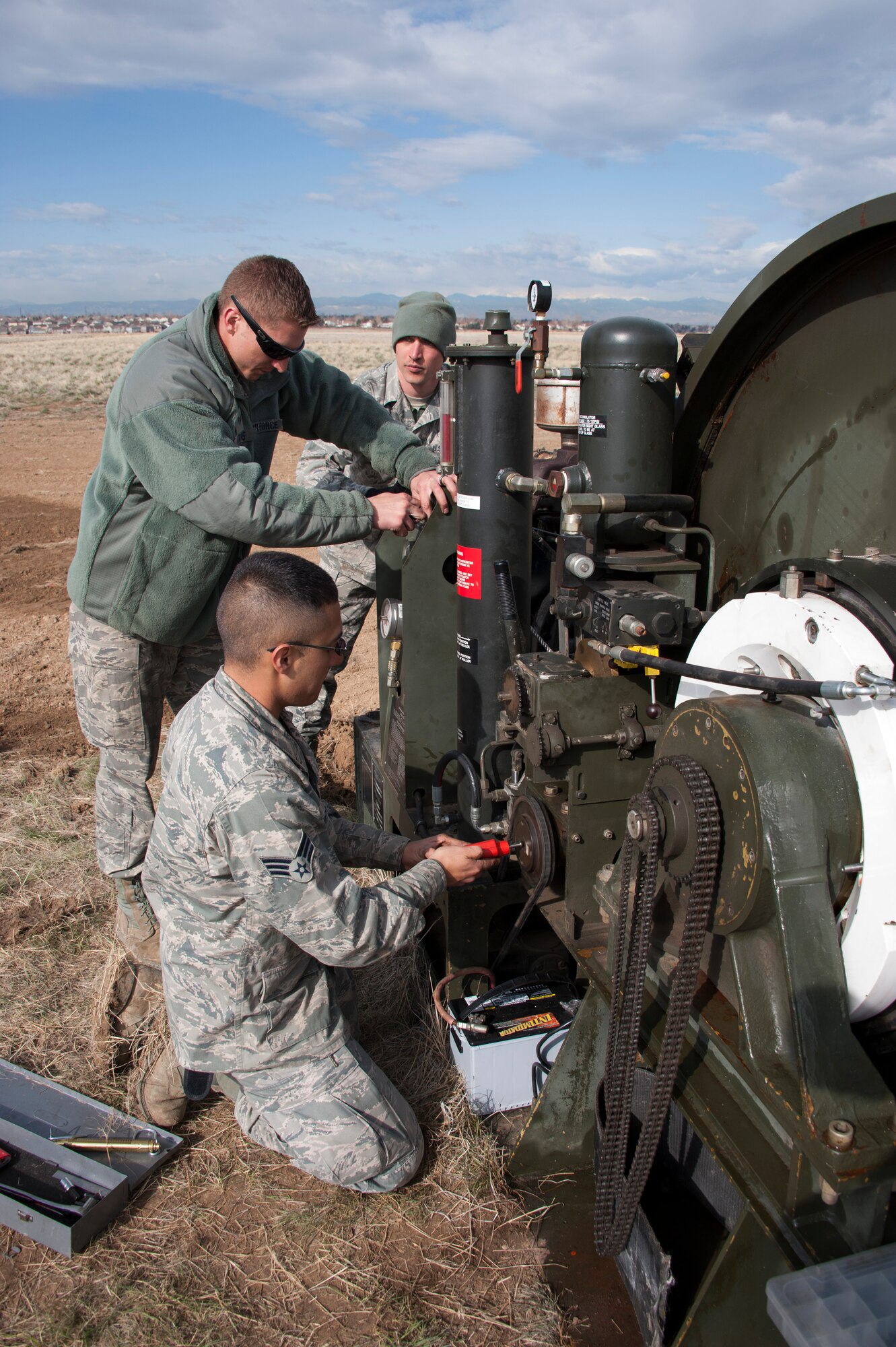 Civil Engineers and a Red Horse Unit are working together to install a BAK-12, Expeditionary Aircraft Arresting System on the main runway at Buckley Air Force Base.  The temporary system must be installed prior to any construction taking place on the runway and so the permanent arresting systems can be upgraded. Senior Airman Jesus Martinez (near) from the 460th Space Warning Squadron, Staff Sgt. Alex Atkins (center) from the 140th Wing and Staff Sgt. Issac Strickler from the 200th Red Horse unit adjust the braking system of the BAK-12 Aircraft Arresting system as part of the installation process.  (U.S. Air National Guard photo by Senior Master Sgt. John Rohrer)