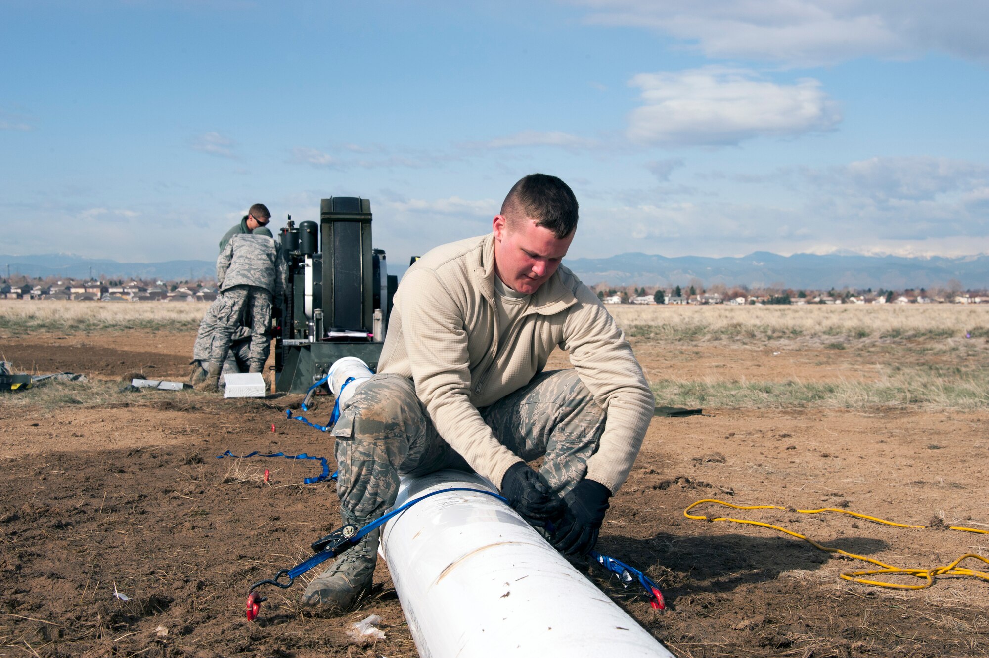 Civil Engineers and a Red Horse Unit are working together to install a BAK-12, Expeditionary Aircraft Arresting System on the main runway at Buckley Air Force Base.  The temporary system must be installed prior to any construction taking place on the runway and so the permanent arresting systems can be upgraded. Senior Airman Jordan Deady, from the 200th RED HORSE Unit, Detachment 1, out of Mansfield, Ohio, ties down the covering for the barrier tape on the arresting system as other civil engineer crewmen adjust the braking system behind him.  (U.S. Air National Guard photo by Senior Master Sgt. John Rohrer)