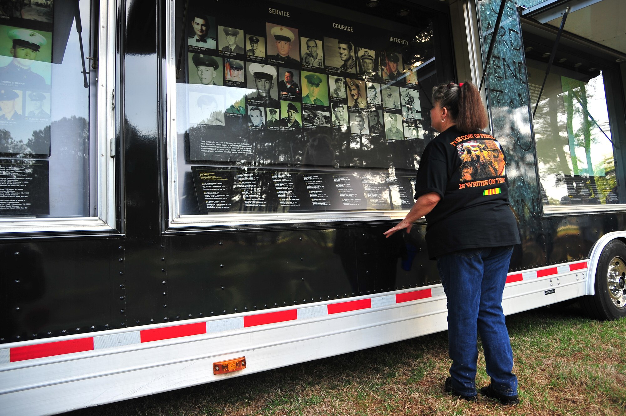 The widow of a fallen Vietnam War veteran admires a display of photos at the Vietnam Veterans Memorial Traveling Wall and museum in Goldsboro, N.C., April 17, 2013. The museum contained photos of service members who made the ultimate sacrifice while defending their nation, as well as relics recovered from the war. (U.S. Air Force photo by Airman 1st Class Aubrey White/Released)