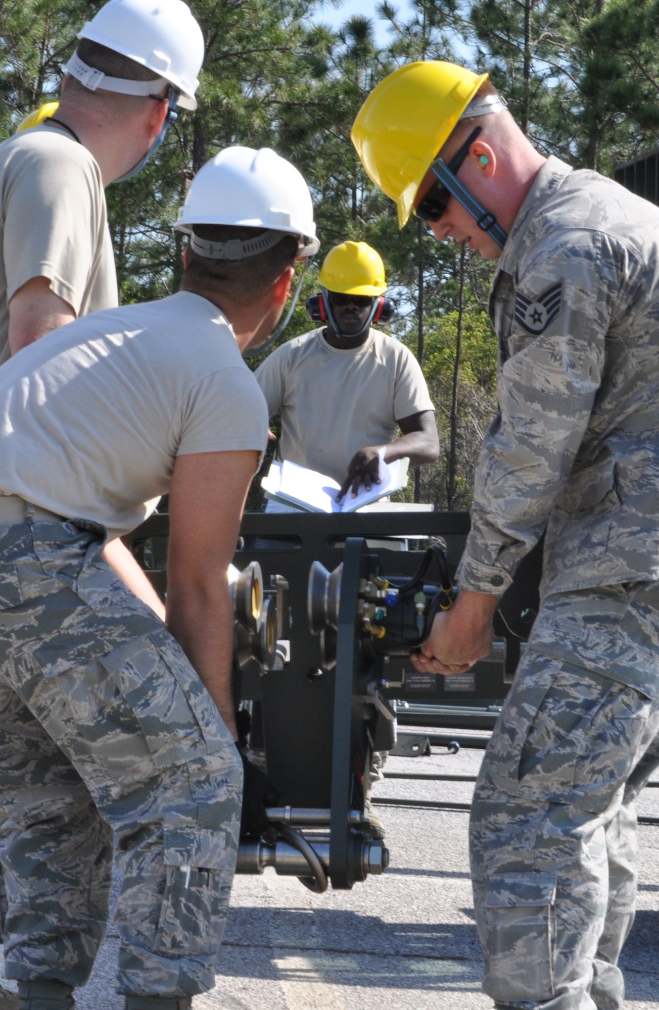 Members of the 325th Maintenance Squadron build the Munitions Assembly Conveyor II for the first time on April 10 in the Alert Facility parking lot on Tyndall Air Force Base. The MAC II is a system that acts as an assembly line for munitions and speeds up the process of their build. (U.S. Air Force photo by Airman 1st Class Alex Echols)