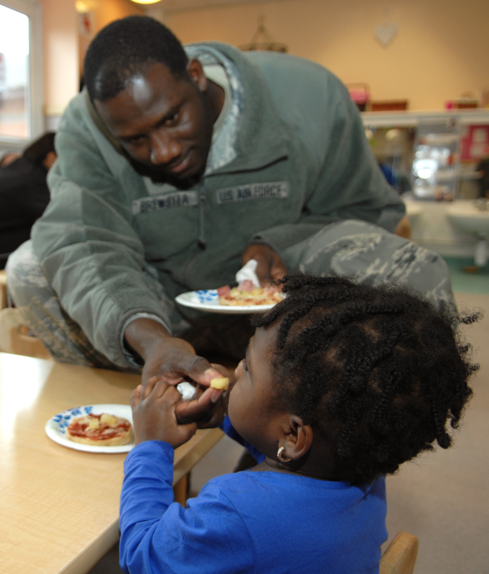 Amiyah Brewster, 1, daughter of Staff Sgt. Carrol Brewster, 100th Communications Squadron local registration authority, eats pizza with her father during a snack picnic April 17, 2013, at the Child Development Center on RAF Mildenhall, England. Children helped to prepare snacks for their parents during the event. (U.S. Air Force photo by Airman 1st Class Dillon Johnston/Released)