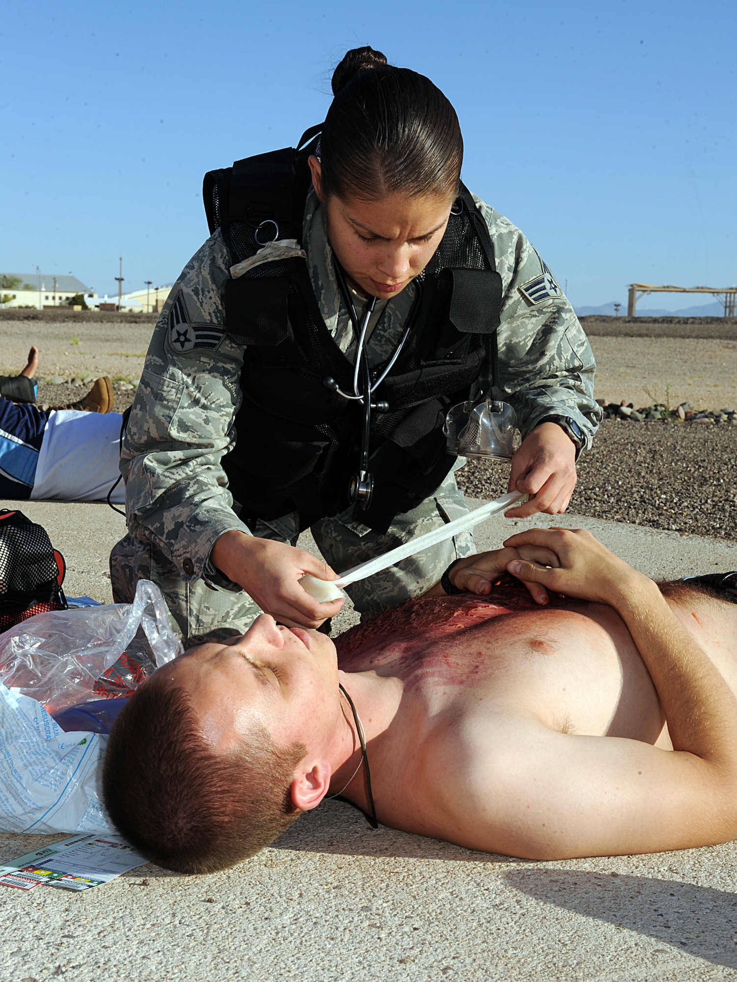 U.S. Air Force Senior Airman Nathania Munoz, 355th Medical Operations Squadron, applies a bandage to a victim of a simulated aircraft crash during Angel Thunder at Davis-Monthan Air Force Base, Ariz., April 13, 2013. The aircraft crash was injected into the emergency medical exercise to train medical personnel should they ever have to deal with a similar situation. (U.S. Air Force photo by Senior Airman Timothy Moore/Released)
