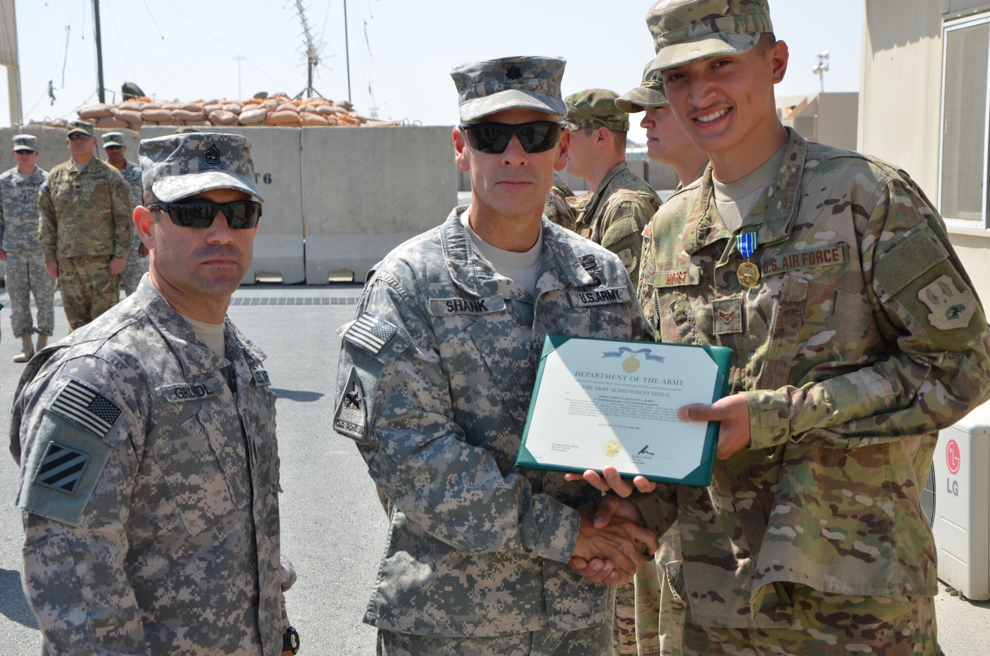 Airman 1st Class Scott Horst, 7th Civil Engineer Squadron, is awarded an Army Achievement Medal from U.S. Army Lt. Col. David E. Shank, 1-43 Air Defense Auxiliary Battalion commander, April 9, 2013. Horst was part of an 18-Airmen team who partnered with the Army’s 1-43 ADA Battalion, to construct more than three miles of roadway and set up a 36-acre site, all while being geographically separated from their supplies. (U.S. Army photo by Capt. Steven Modugno/Released)