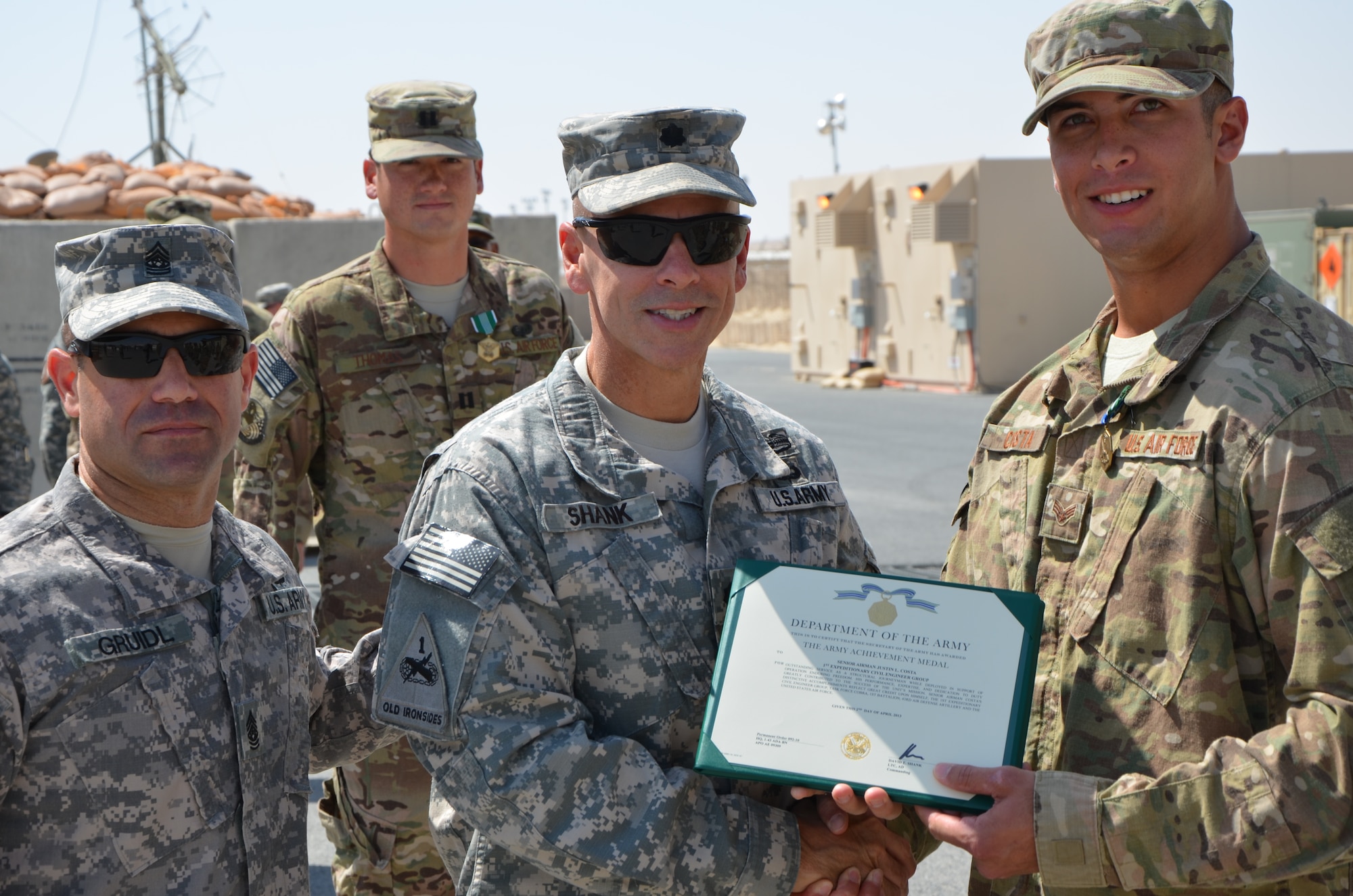 Senior Airman Justin Costa, 7th Civil Engineer Squadron, is awarded an Army Achievement Medal from U.S. Army Lt. Col. David E. Shank, 1-43 Air Defense Auxiliary Battalion commander, April 9, 2013. Costa was part of an 18-Airmen team who partnered with the Army’s 1-43 ADA Battalion, to construct more than three miles of roadway and set up a 36-acre site, all while being geographically separated from their supplies. (U.S. Army photo by Capt. Steven Modugno/Released)