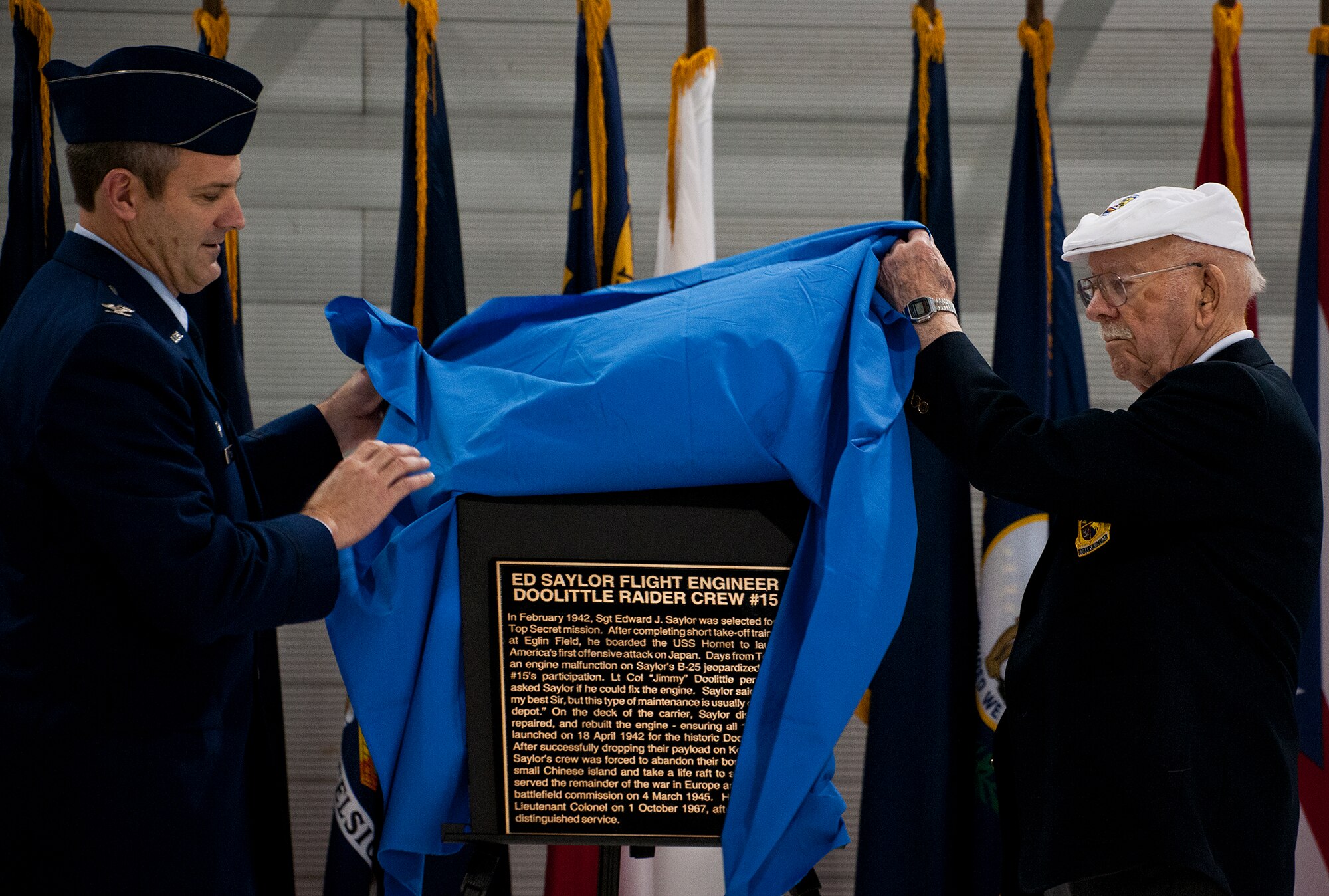 Doolittle Raider, Lt. Col. Ed Saylor, and Col. Andrew Toth, the 33rd Fighter Wing commander, unveil the honorary plaque during a hangar dedication in honor of Saylor April 17 at Eglin Air Force Base, Fla.  After unveiling the plaque, Saylor spoke about his experiences in the military and with the historic Raiders.  For the ceremony, an F-35A Lightning II and a Doolittle Raider B-25 were parked side by side in the hangar.  (U.S. Air Force photo/Samuel King Jr.)