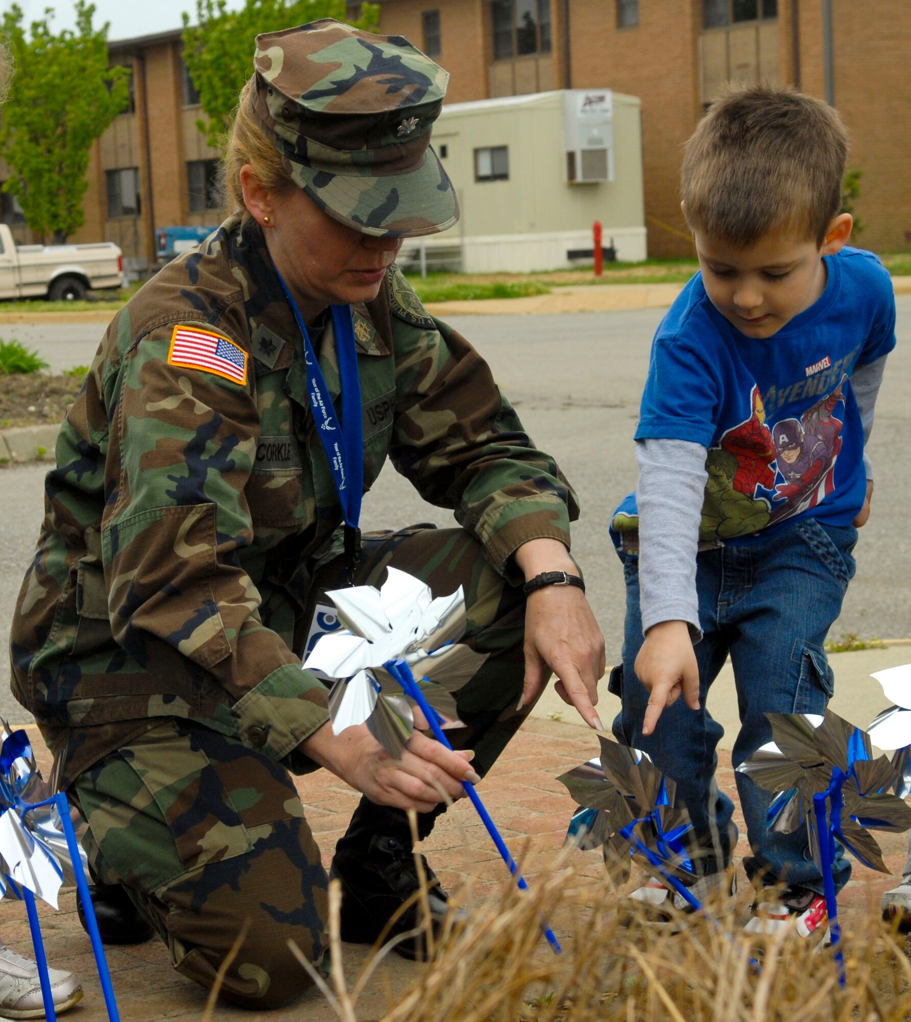 U.S. Public Health Service Cmdr. Jenny McCorkle, 633rd Medical Group Family Advocacy Program officer-in-charge, helps a young boy place his pinwheel to raise awareness about child maltreatment at Langley Air Force Base, Va., April 15, 2013. The pinwheel, in addition to the blue ribbon, symbolizes April as Child Abuse Prevention Month. (U.S. Air Force photo by Airman 1st Class Austin Harvill/Released)