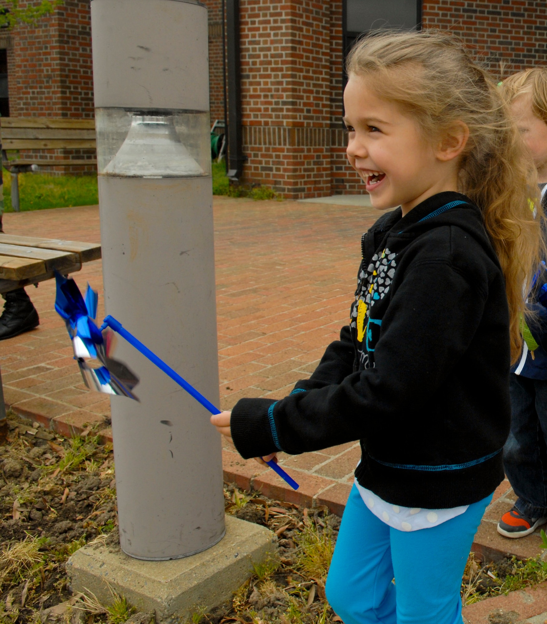 A military child rushes to plant her pinwheel to raise awareness about child maltreatment at Langley Air Force Base, Va., April 15, 2013. Children from the General Russ Child Development Center planted pinwheels in front of the CDC to raise awareness of child abuse and maltreatment. (U.S. Air Force photo by Airman 1st Class Austin Harvill/Released)