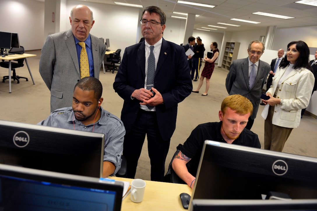 Acuitus CEO John Newkirk, left, shows Deputy Defense Secretary Ash Carter, center, how the company trains veterans to write software code in Palo Alto, Calif., April 17, 2013.