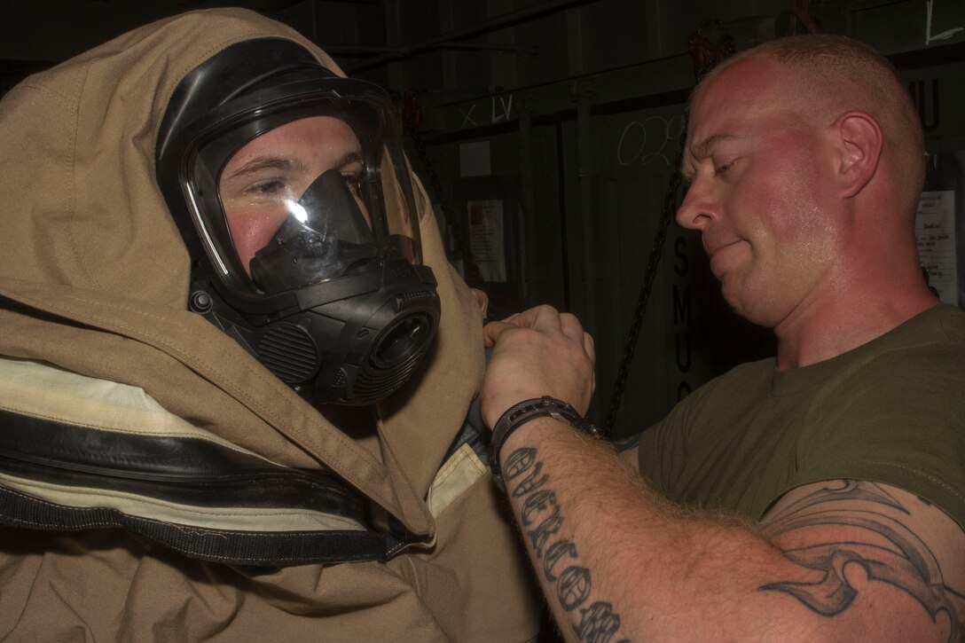 U.S. Marine Staff Sgt. Robert Manion, chemical, biological, radiological and nuclear (CBRN) defense and assessment consequence management chief, 26th Marine Expeditionary Unit (MEU), assists Lance Cpl. Cody Kirsthart, 26th MEU CBRN defense specialist, conduct a level B hazardous material suit familiarization exercise aboard the USS Kearsarge (LHD 3) while at sea April 17, 2013. The 26th MEU is deployed to the 5th Fleet area of operations aboard the Kearsarge Amphibious Ready Group. The 26th MEU operates continuously across the globe, providing the president and unified combatant commanders with a forward-deployed, sea-based quick reaction force. The MEU is a Marine Air-Ground Task Force capable of conducting amphibious operations, crisis response and limited contingency operations.