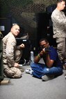 Cpl. William Robinson (left), a marksmanship instructor with the Basic Skills Training School, 2nd Marine Logistics Group, watches Duane Adams (right), a student with Northeast Guilford High School, as he prepares to fire during a base tour aboard Camp Lejeune, N.C., April 18, 2013.  The students went in groups of four, shooting in the sitting, kneeling and standing position.
